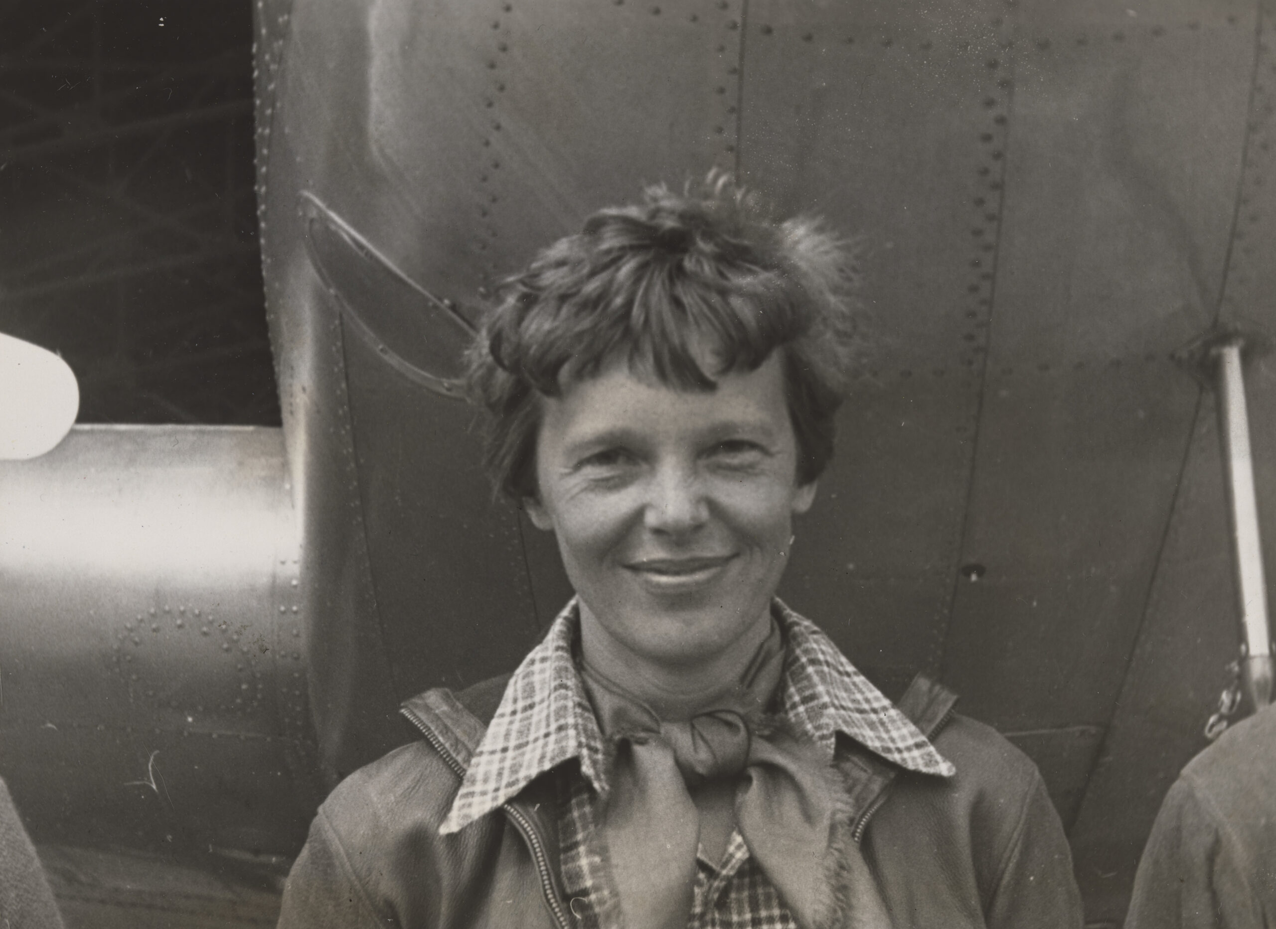 Amelia Earhart standing beneath the nose of her Lockheed Model 10-E Electra