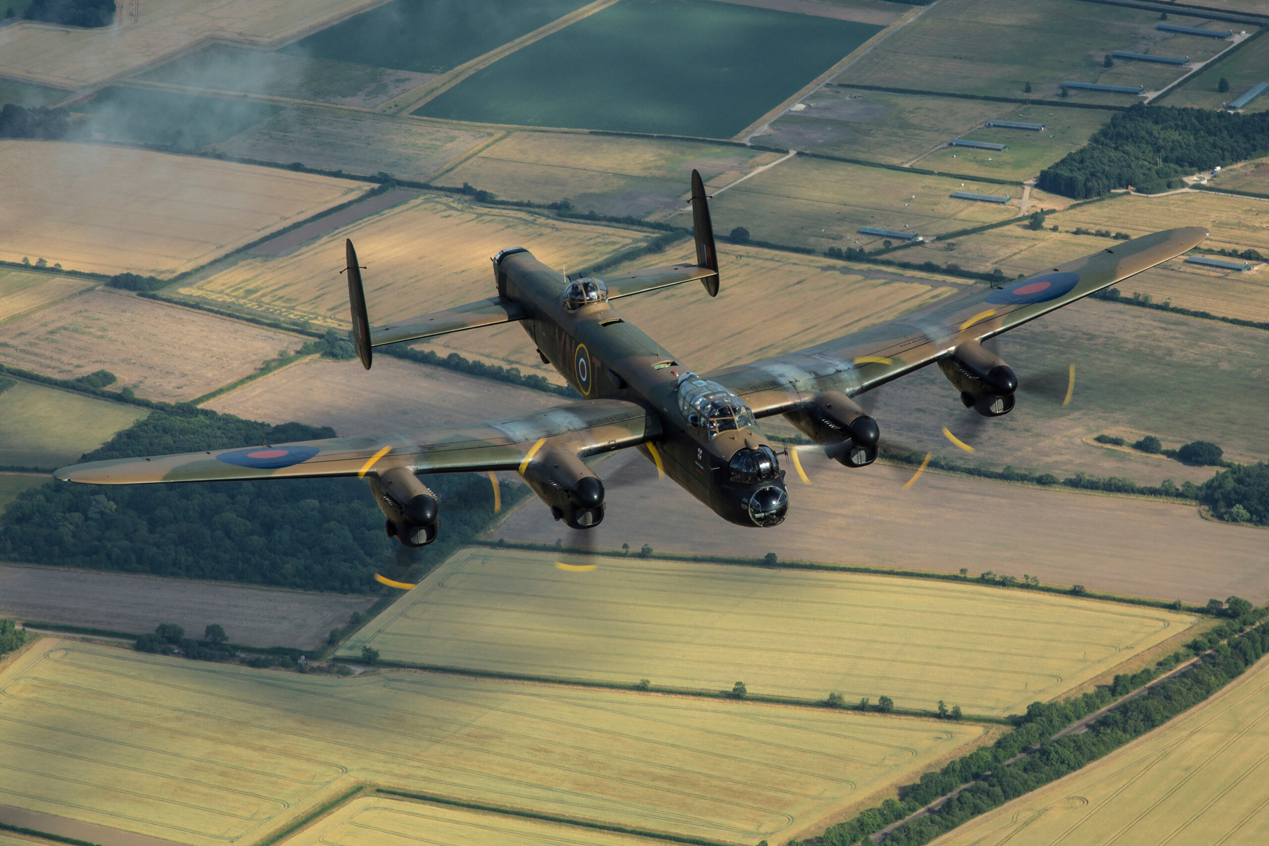 Avro Lancaster PA474 of the Battle of Britain Memorial Flight banking over farmland, all four Merlins turning