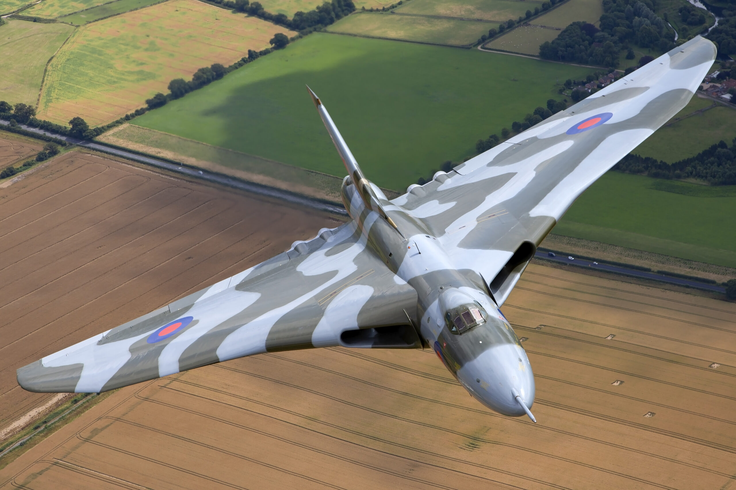 Avro Vulcan XH558 topside planform over golden harvest fields, photographed air to air