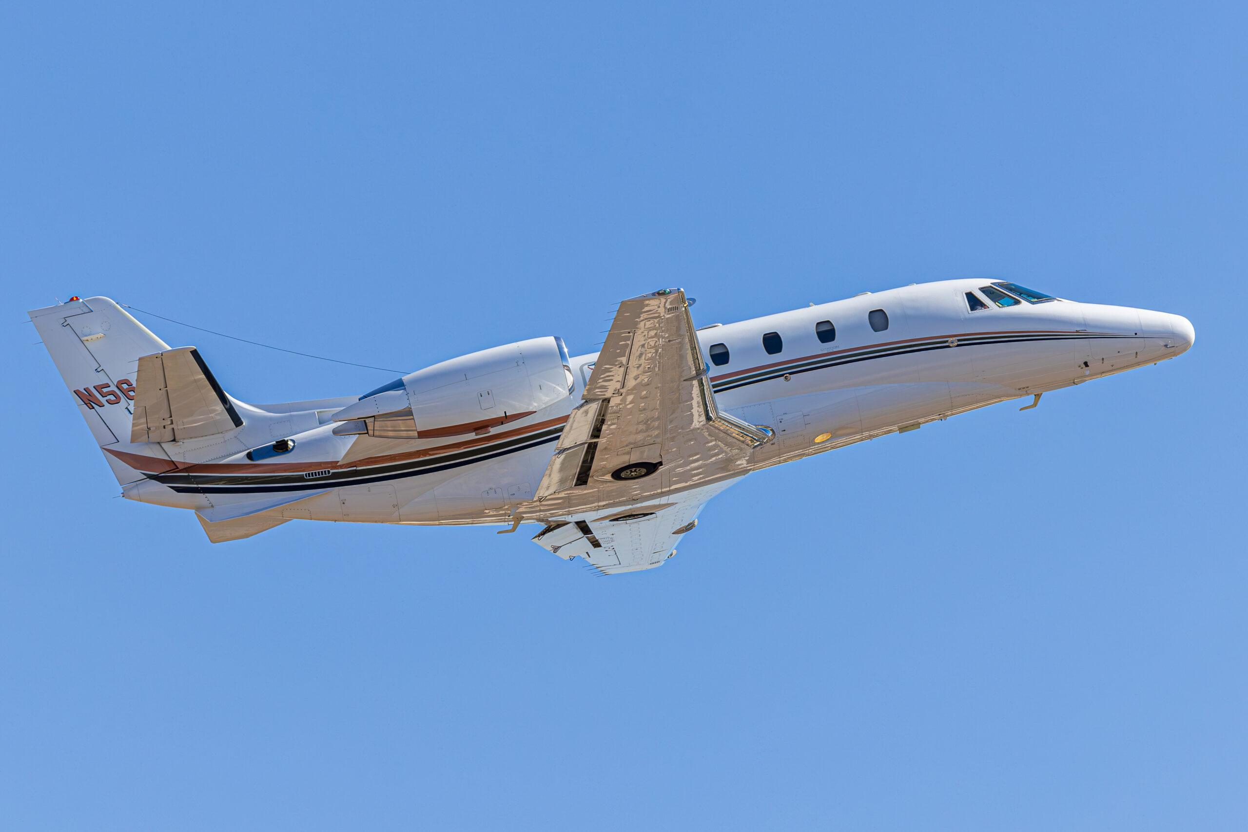 Business jet climbing steeply against a clean blue sky after departing Scottsdale Airport