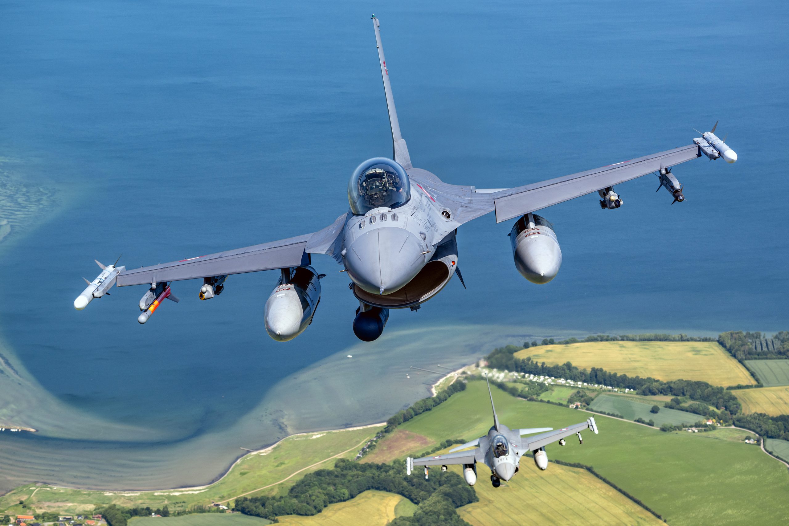 Two Royal Danish Air Force F-16s head-on in formation over the Danish coastline