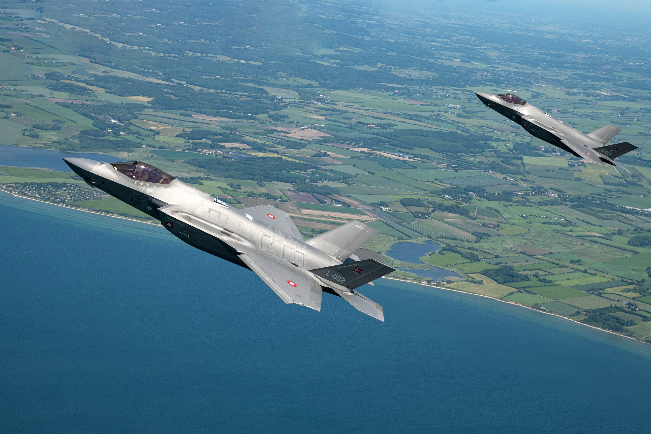 Two Royal Danish Air Force F-35As in echelon over the Danish coastline