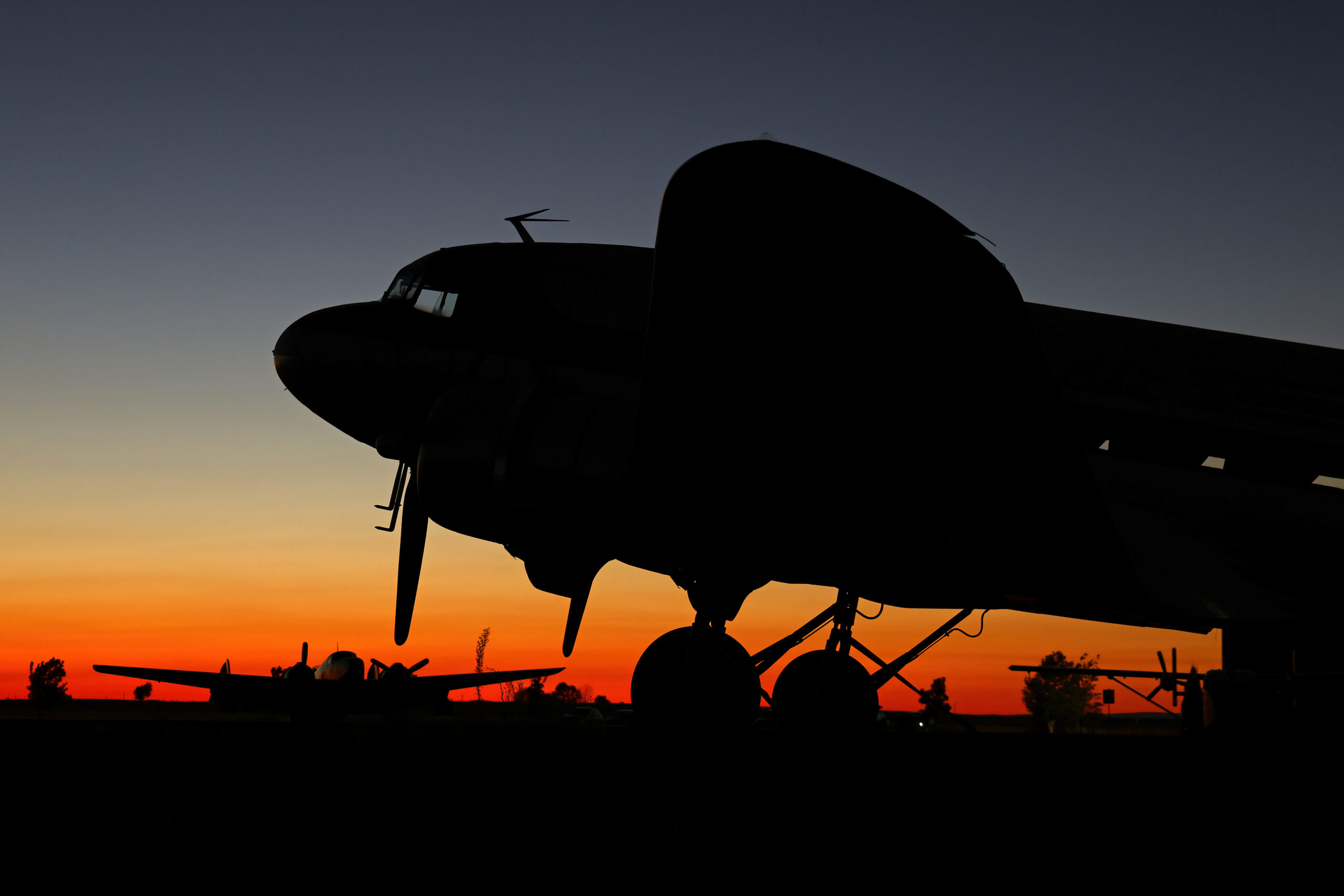 Douglas C-47 Skytrain silhouetted against a sunset sky