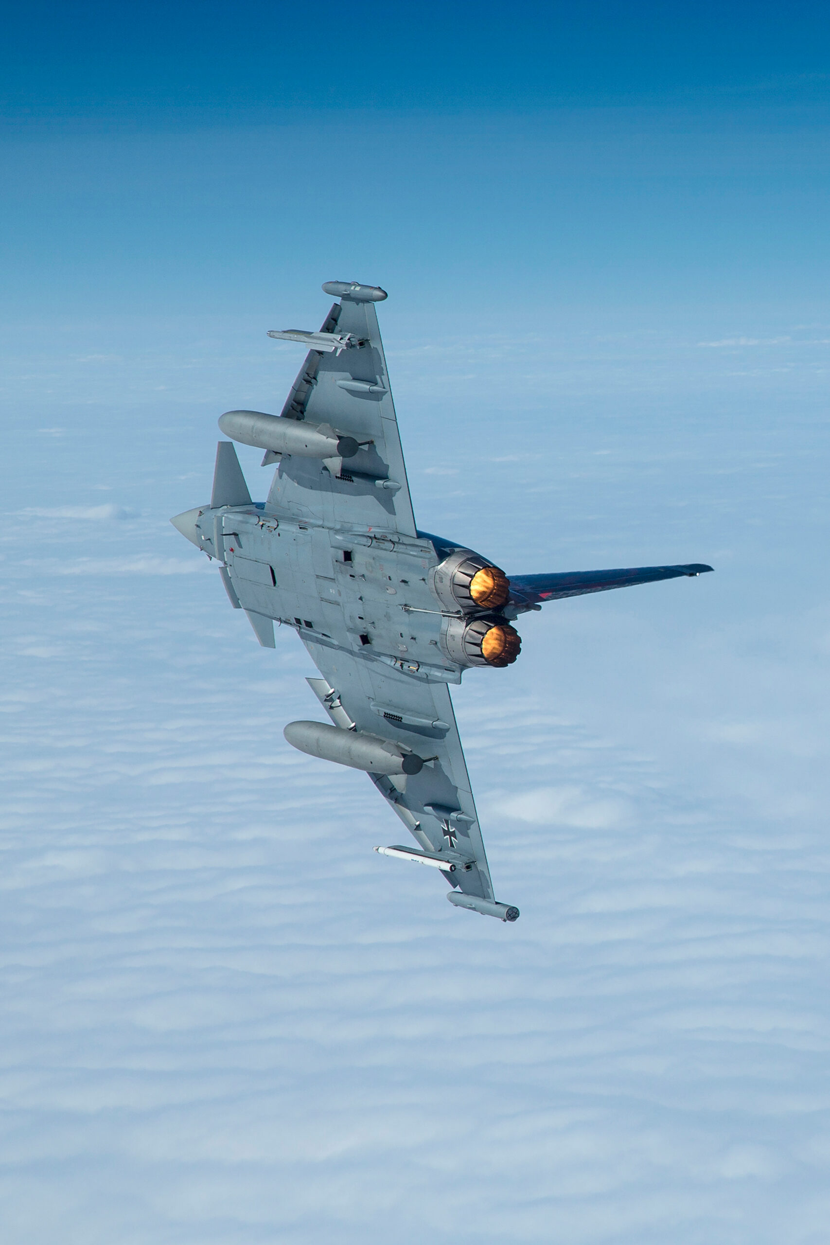 Eurofighter Typhoon climbing with both afterburners lit against a blue sky