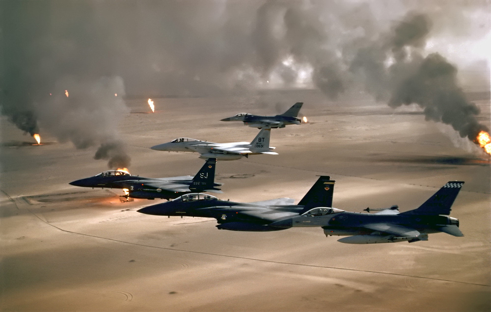 USAF F-15C, F-15E and F-16 aircraft flying over burning Kuwaiti oil fields in 1991