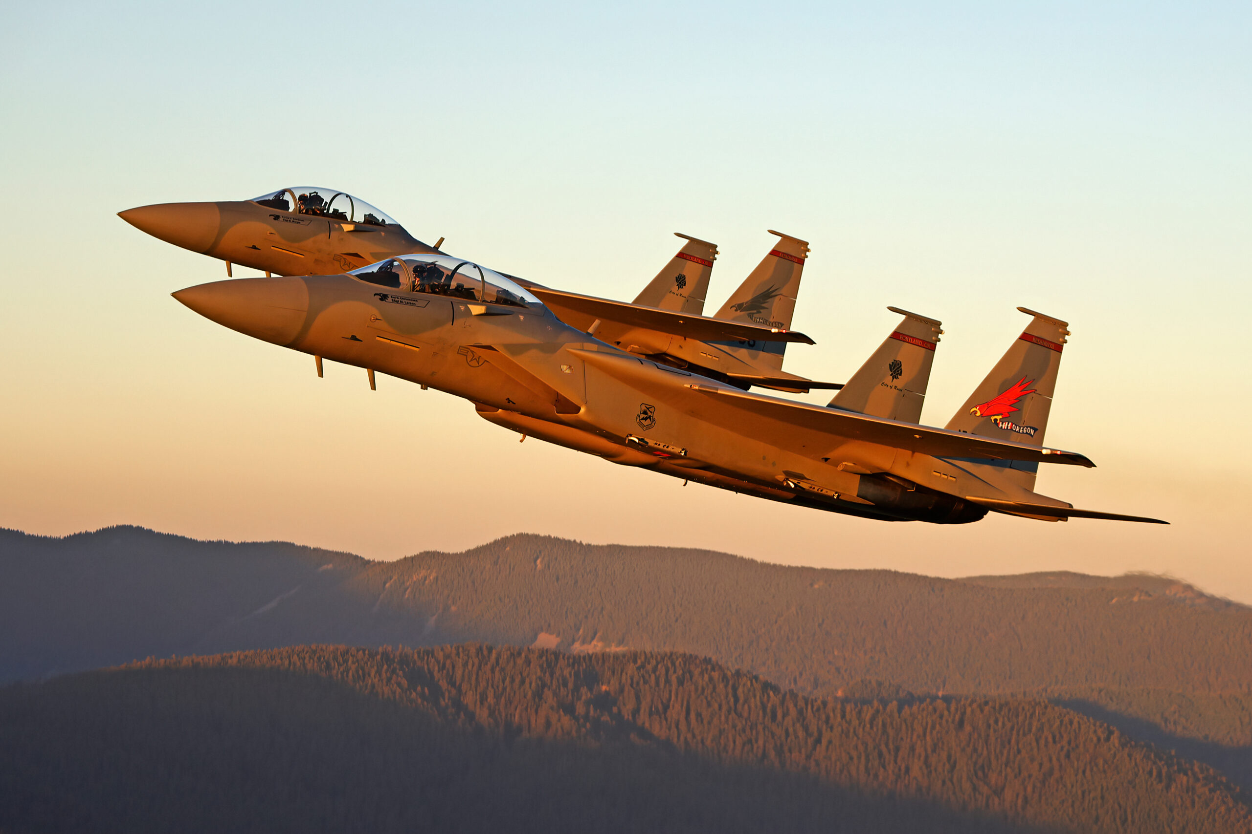 Two F-15EX Eagle IIs of the 142nd Wing air to air in golden light over mountains