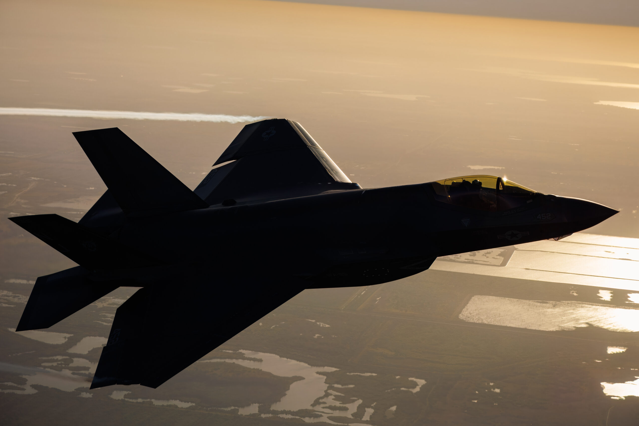 US Navy F-35C in near-silhouette against golden haze