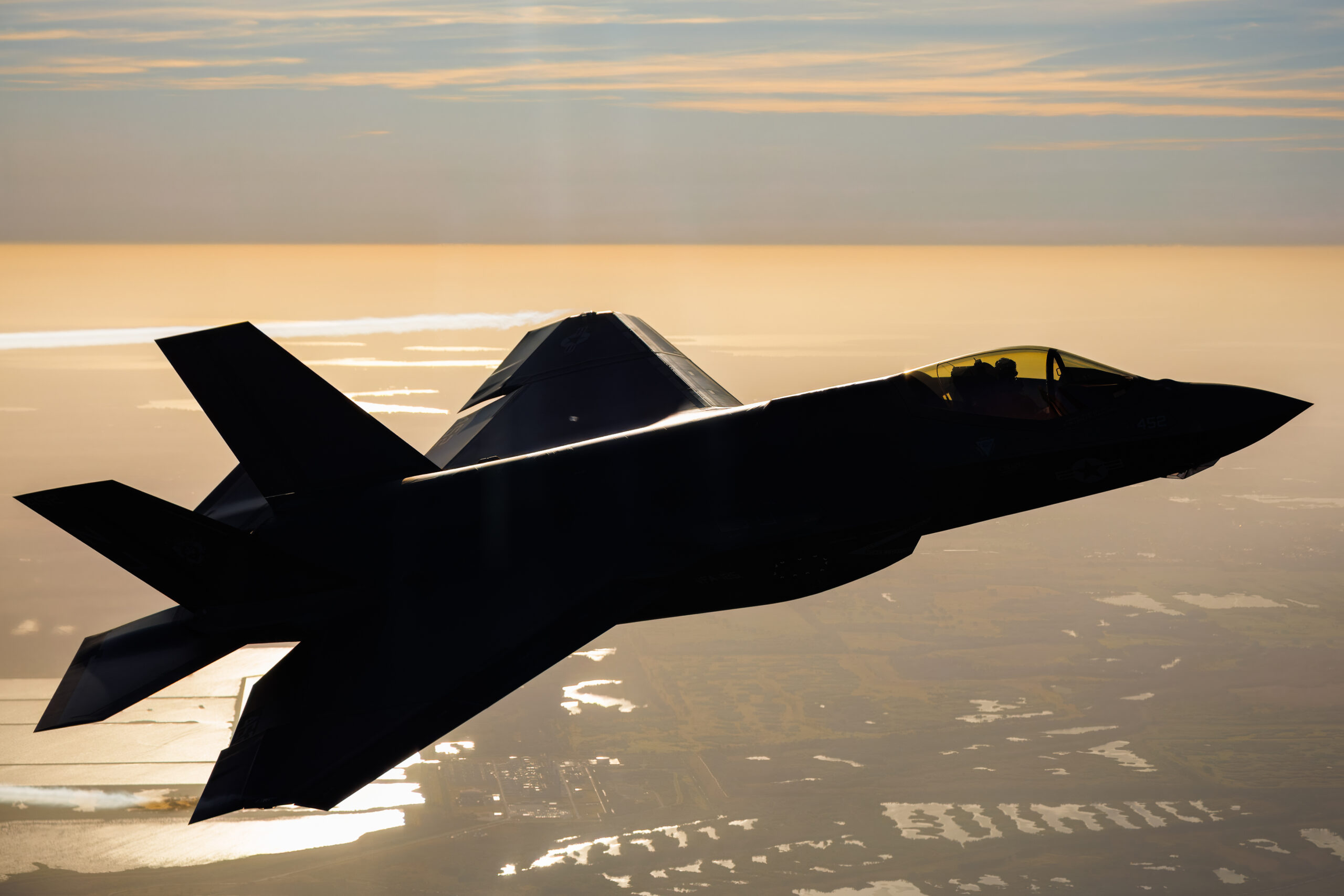 US Navy F-35C in near-silhouette against golden haze