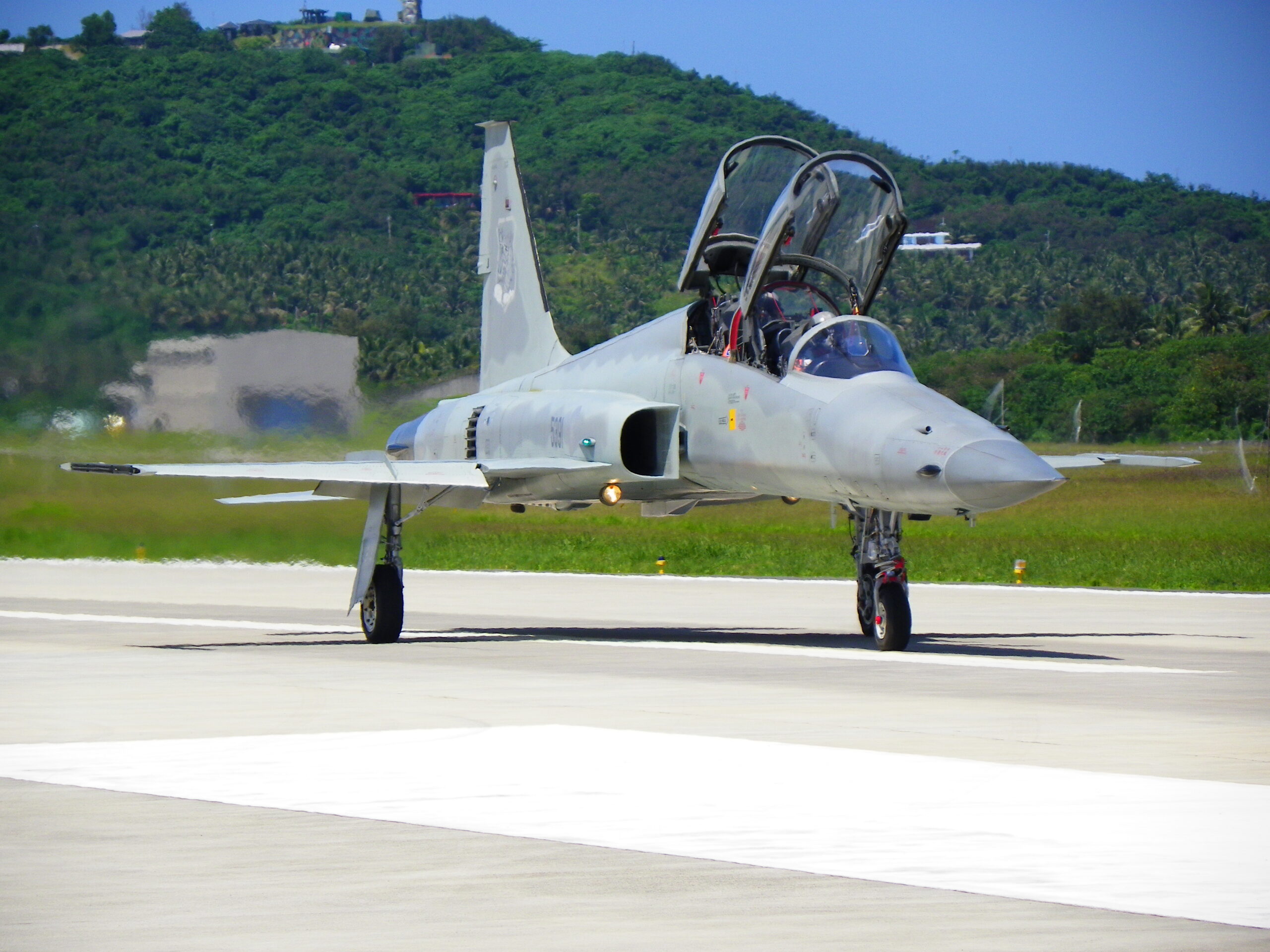 F-5F fighter taxiing on a sun-baked runway with heat rising off the tarmac