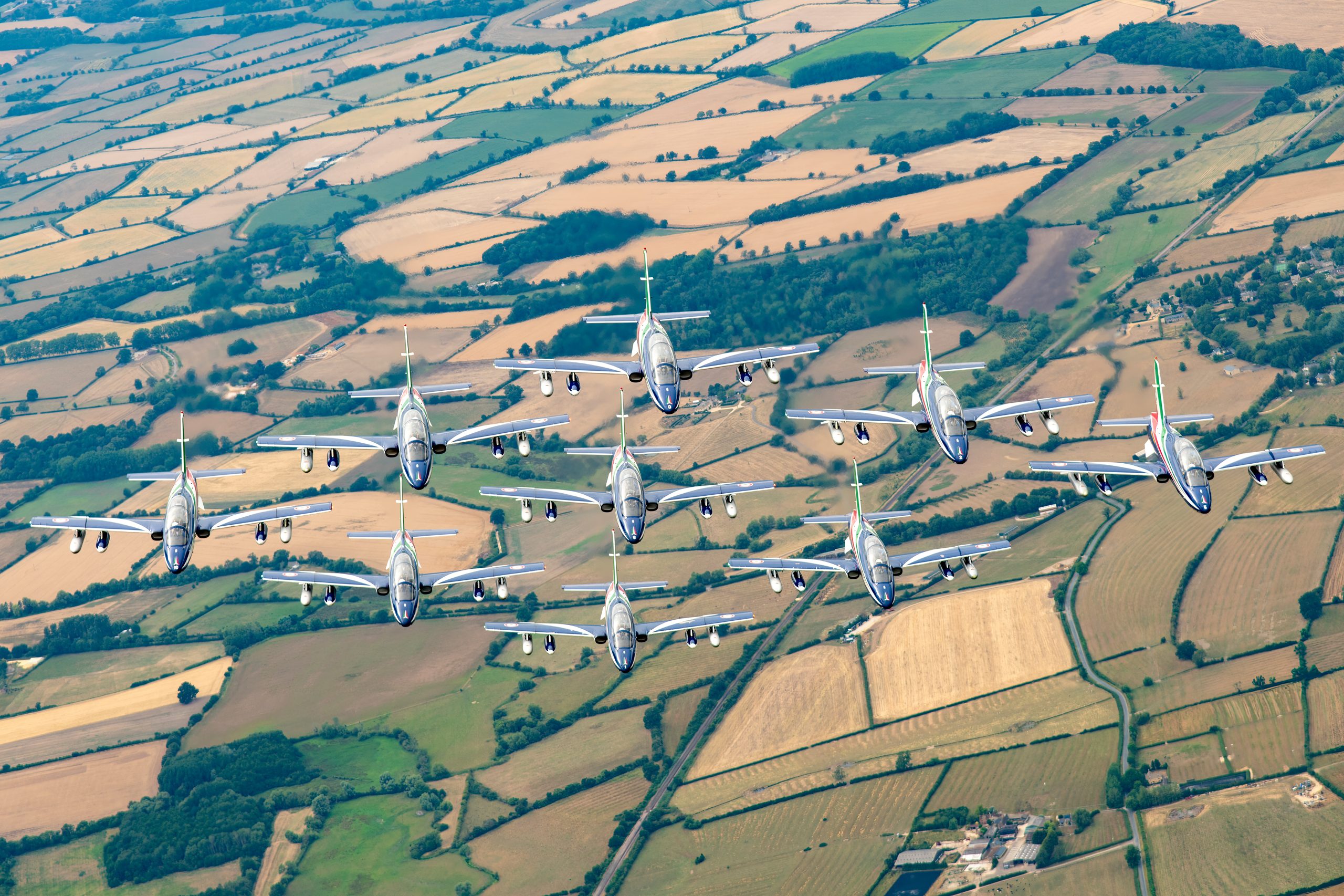 Italian Air Force Frecce Tricolori Aermacchi MB-339 jets in formation air to air over English fields