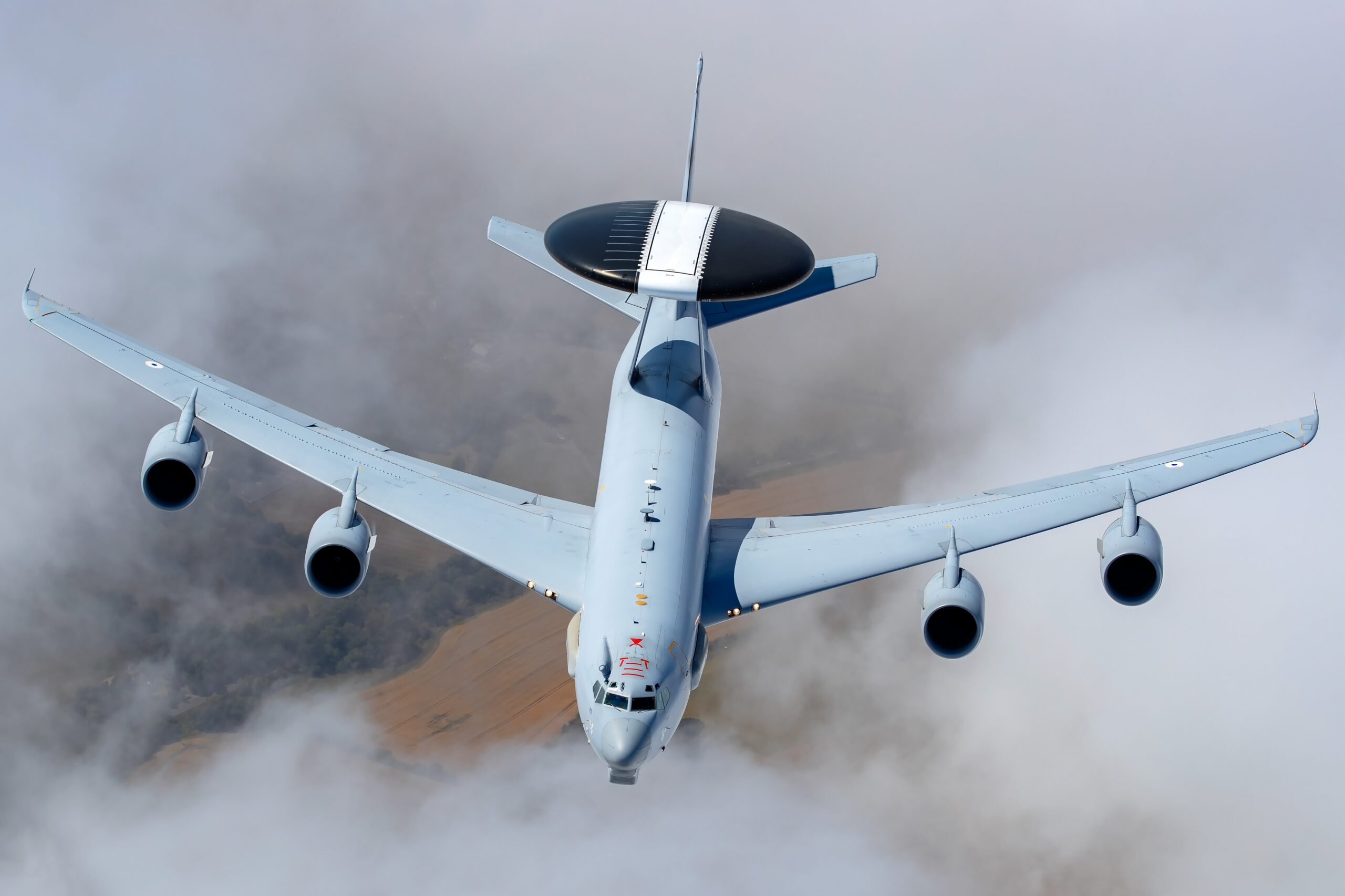 French Air Force E-3F Sentry with its black rotodome, banking head-on above cloud
