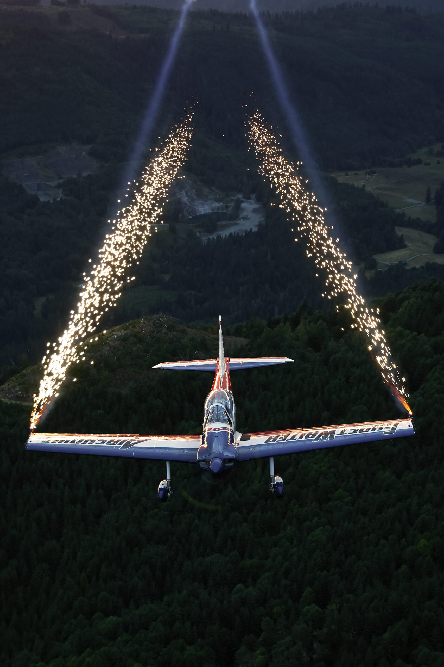 GhostWriter Super Chipmunk head-on at dusk with pyrotechnic sparks streaming from the wingtips