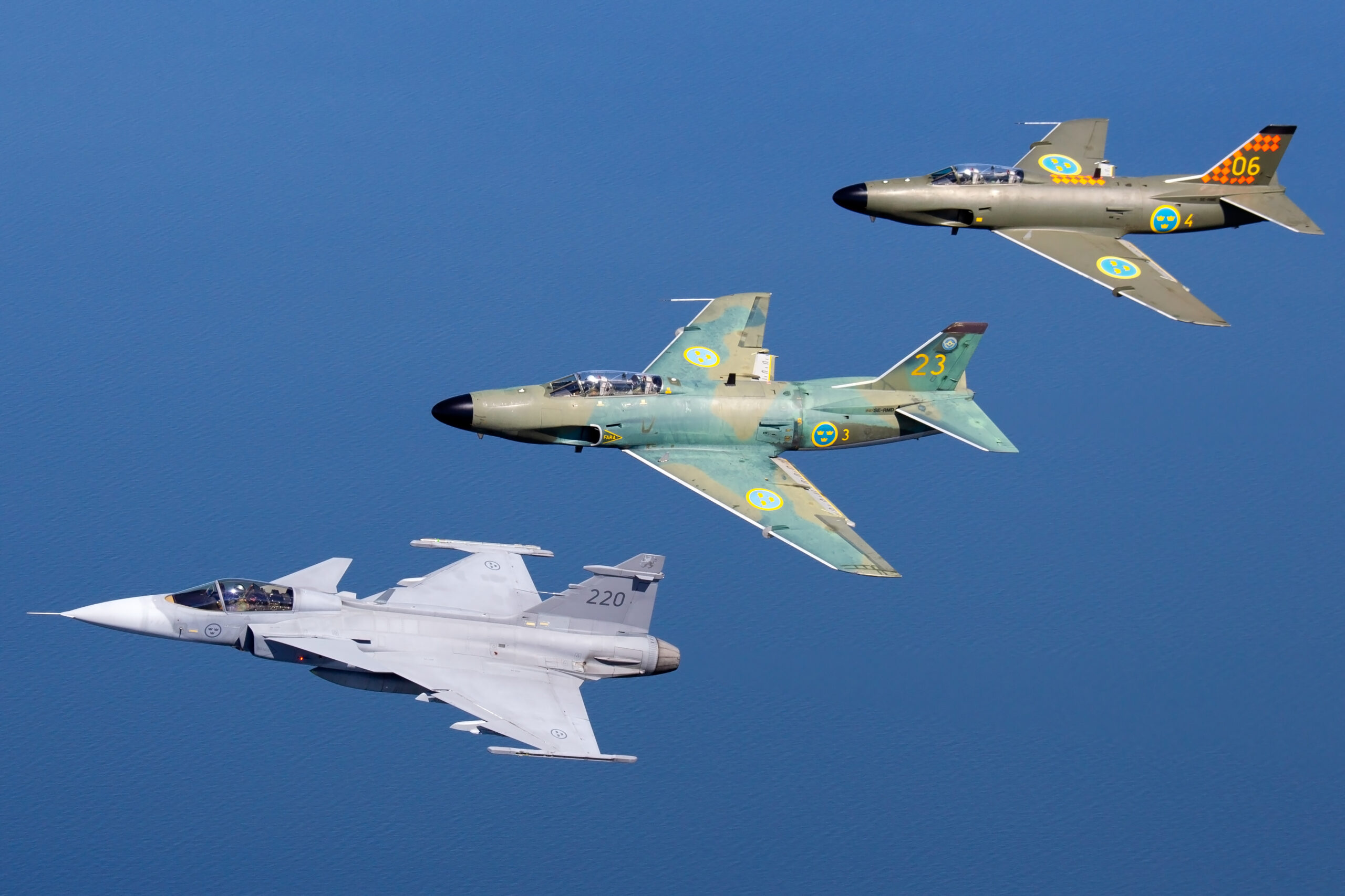 Saab JAS-39C Gripen leading two Saab 32 Lansens in a mixed three-ship formation over the sea
