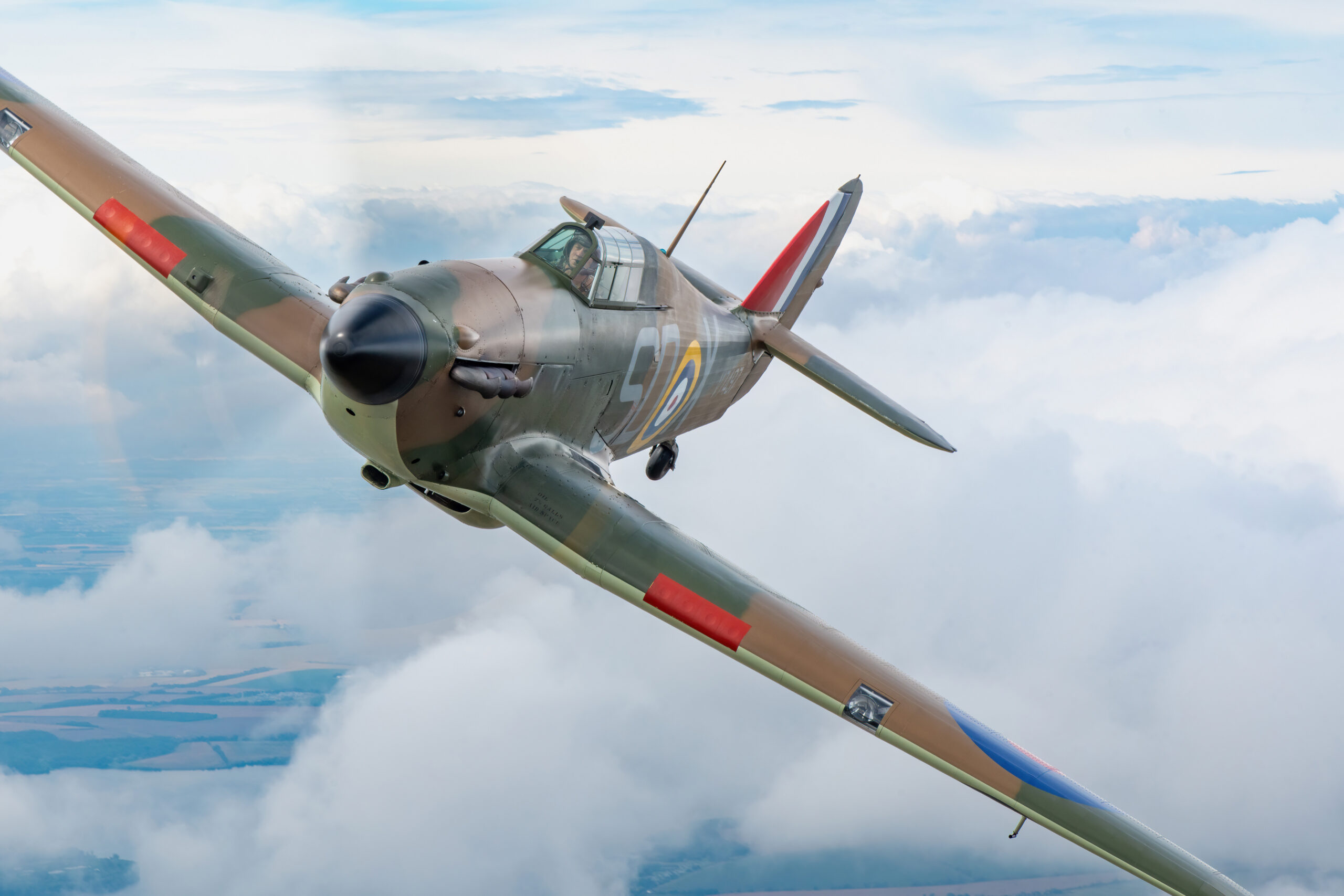 Hawker Hurricane Mk I in Battle of Britain camouflage banking towards the camera above clouds