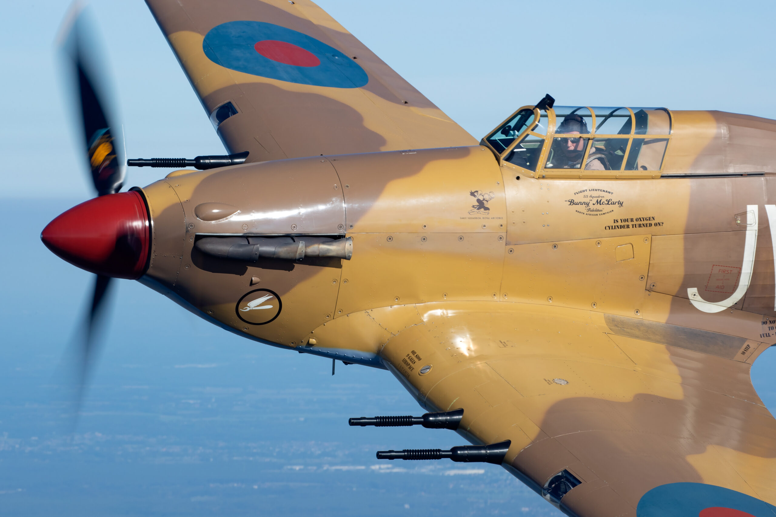 Tight air-to-air close-up of a Hawker Hurricane with the pilot visible in the cockpit