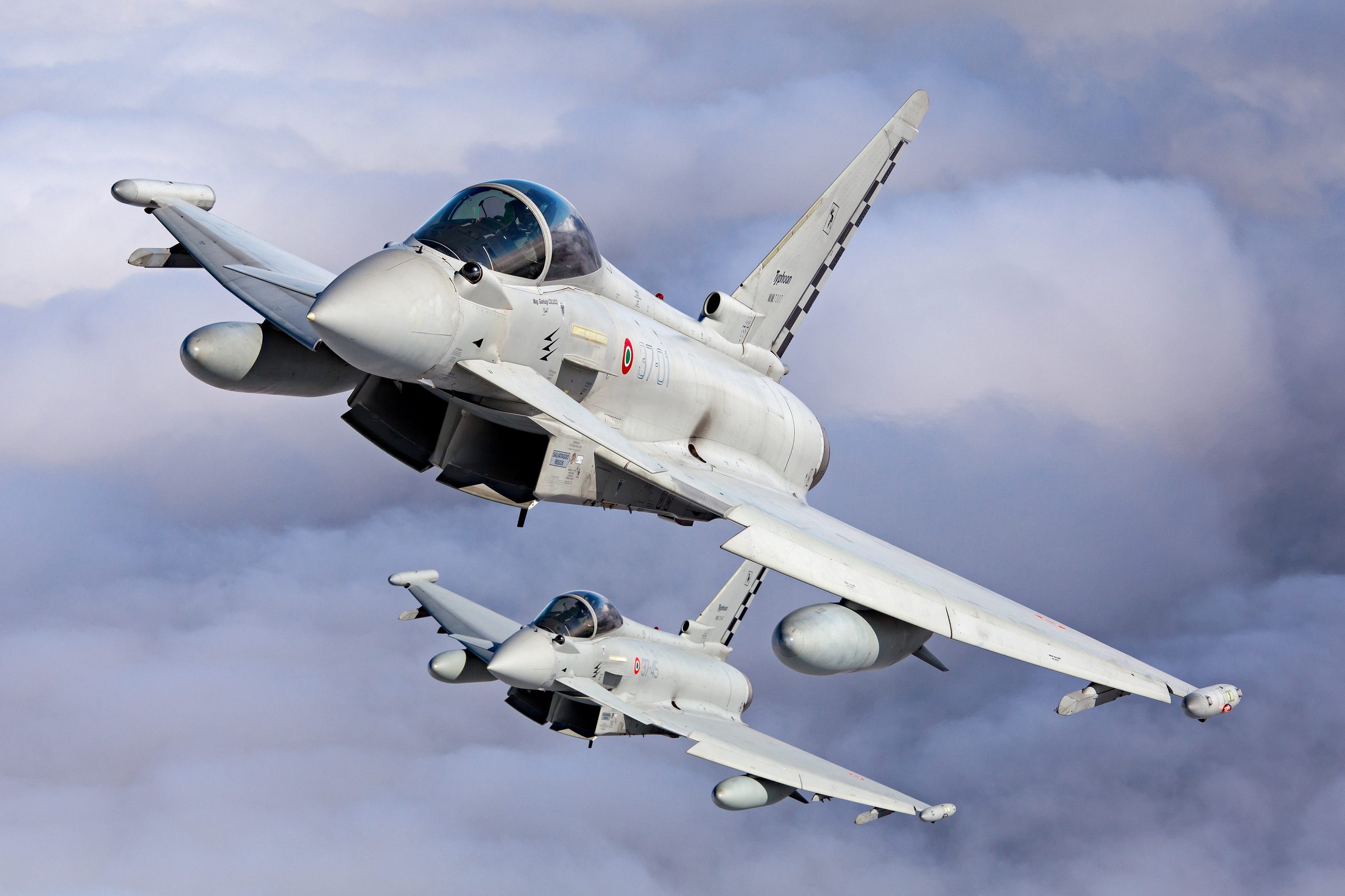Italian Air Force Typhoon 37-01 with checkerboard tail leading 37-45 in formation against dramatic grey cloud