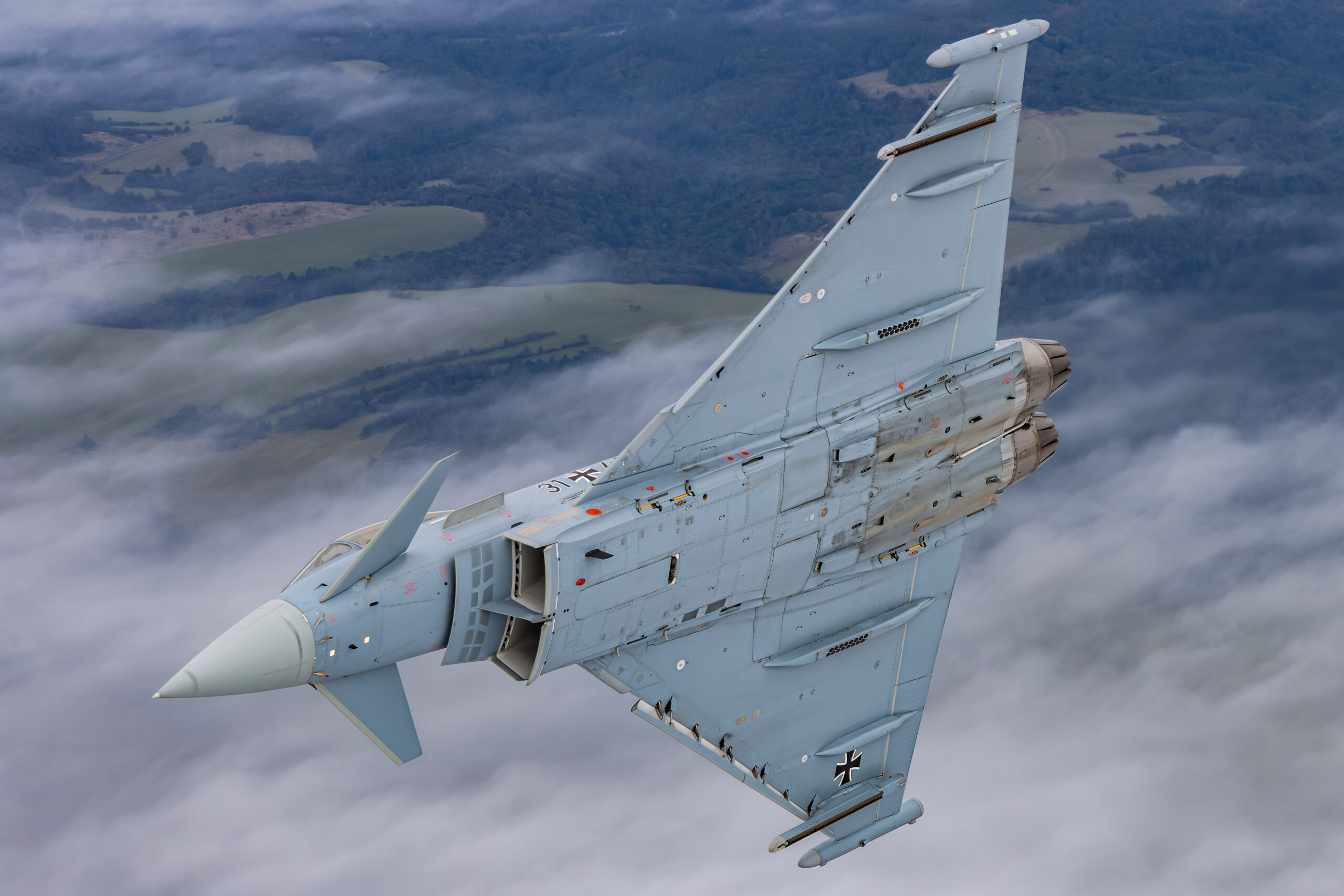 German Air Force Eurofighter Typhoon banking hard over low cloud, showing its full underside