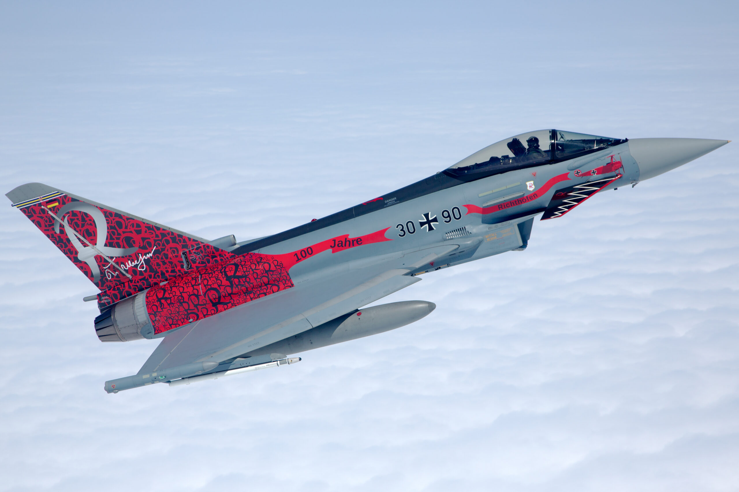 Luftwaffe Eurofighter Typhoon 30+90 in the red and grey Richthofen 100 Jahre special scheme flying above an unbroken cloud deck, pilot visible