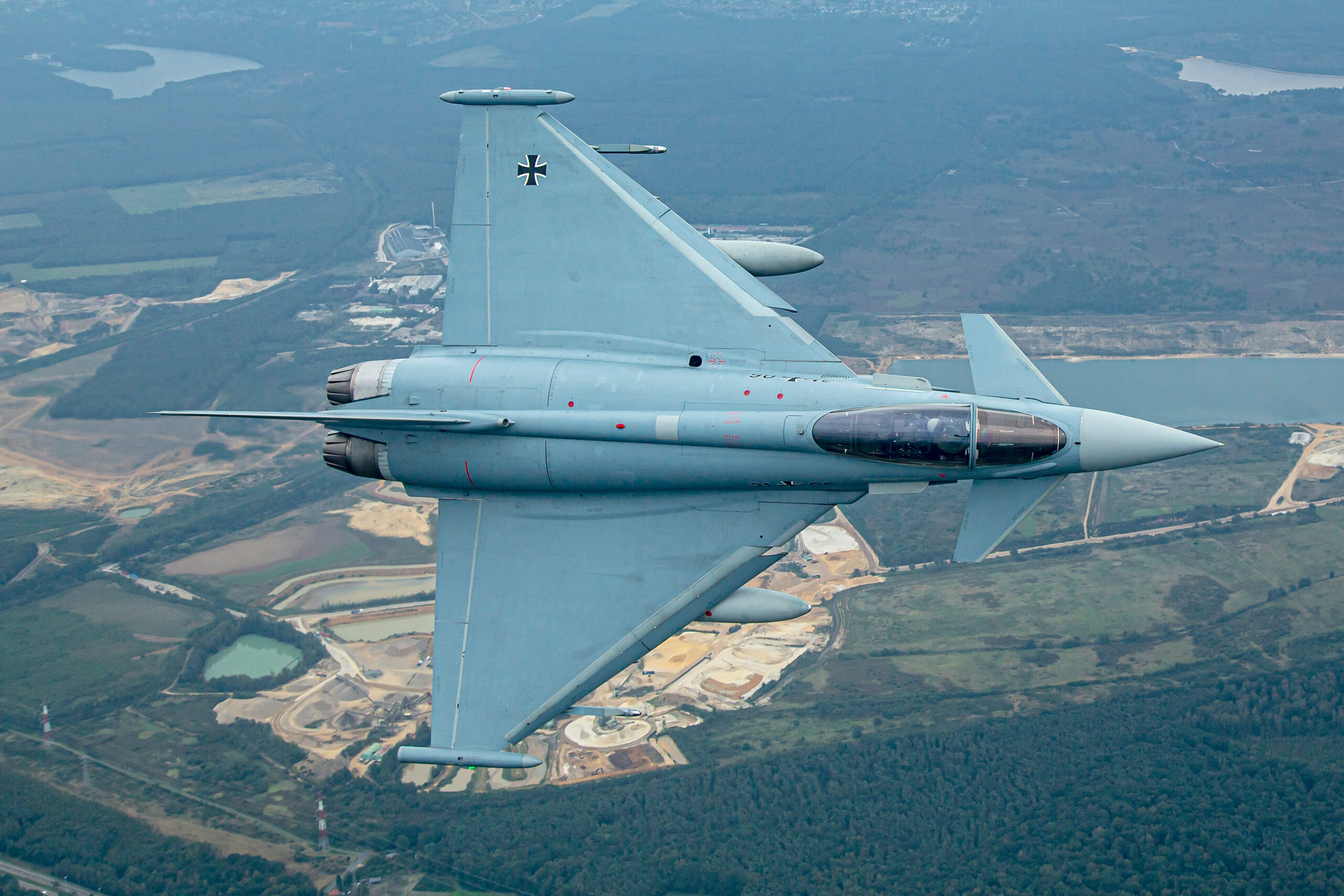 Full topside planform of Luftwaffe Typhoon 31+06 banking steeply over lakes, quarries and woodland, delta wing and canards clearly visible