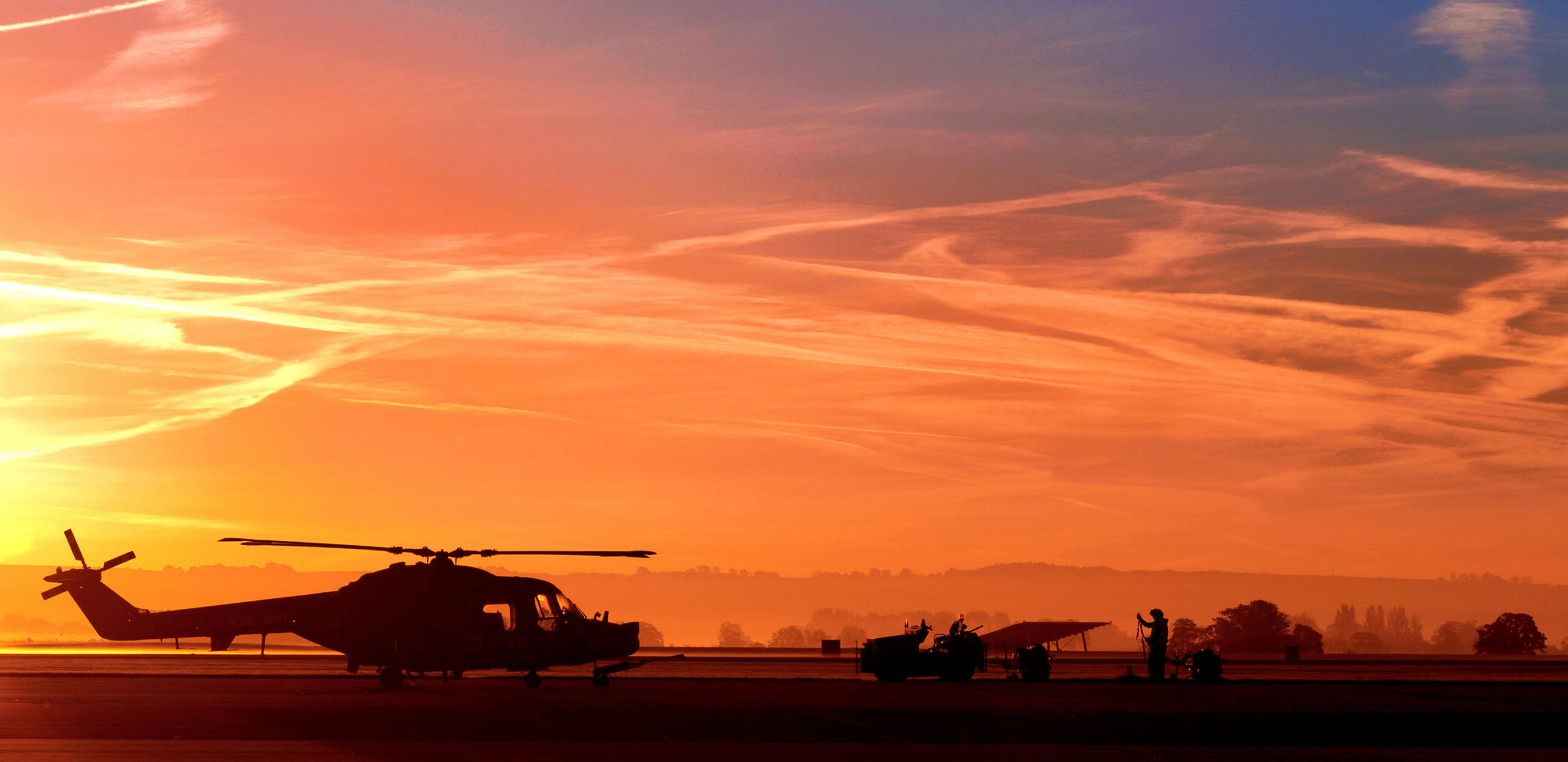 Ground crew preparing a Lynx Mk3 helicopter at sunrise at RNAS Yeovilton