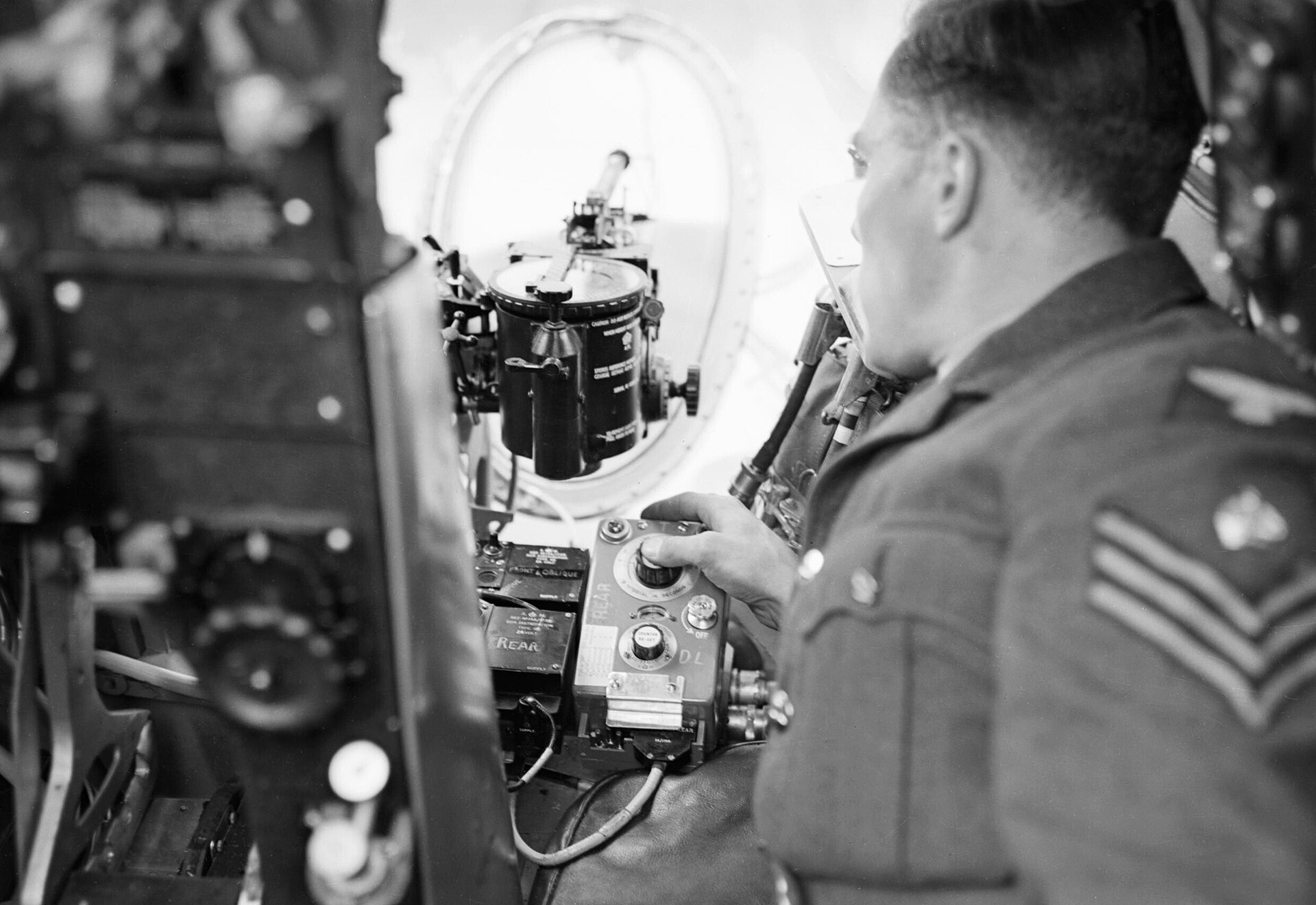 Ground crew flight sergeant demonstrating the photo-reconnaissance camera in a de Havilland Mosquito of No. 540 Squadron RAF at Benson, August 1943