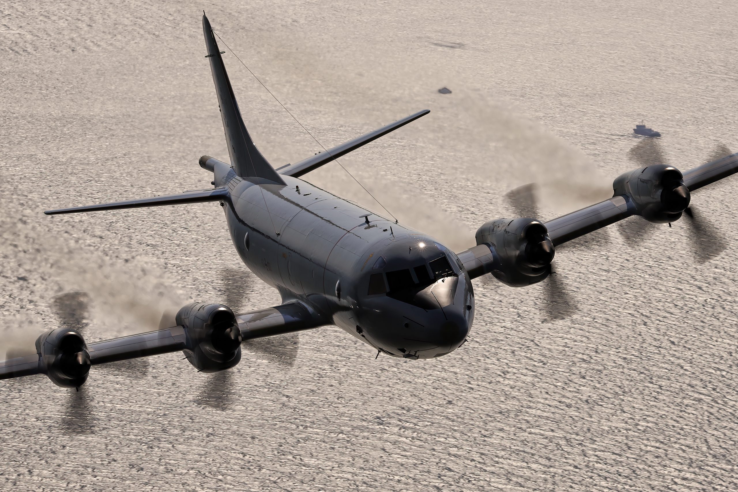 P-3C Orion backlit and dark against a silvery sun-glinted sea