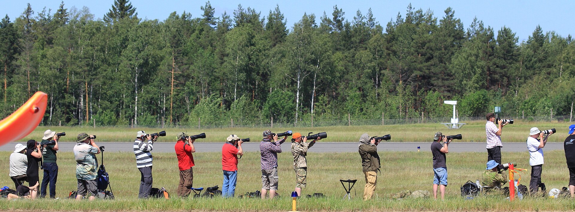 Row of plane spotters with telephoto lenses on the crowd line at an airshow