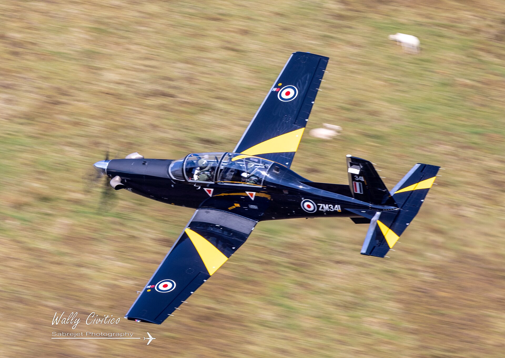 RAF Texan T1 ZM341 banking through the Mach Loop at Cad East with a motion-blurred hillside behind