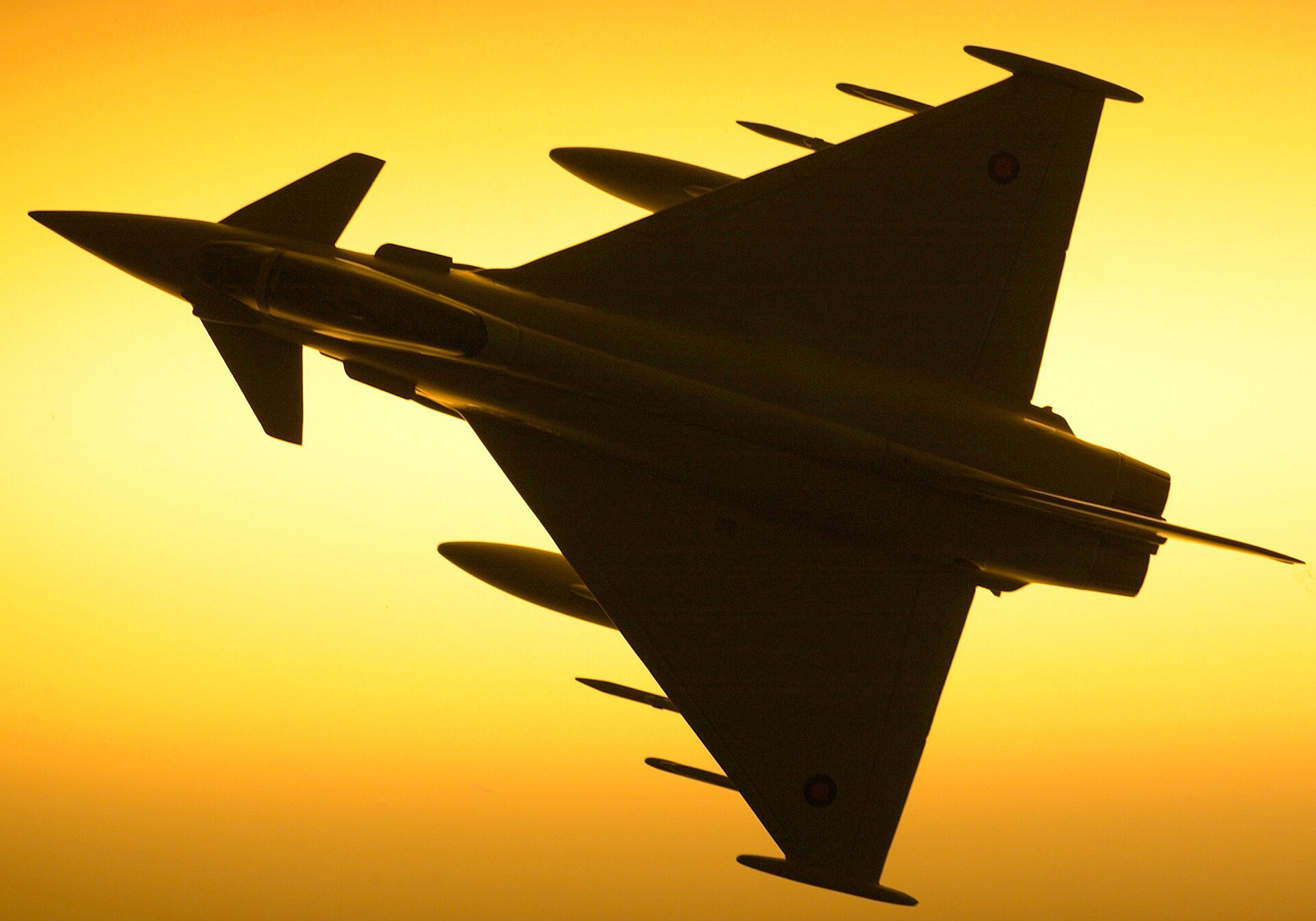 Royal Air Force Typhoon F2 silhouetted against a bright sky as it passes overhead