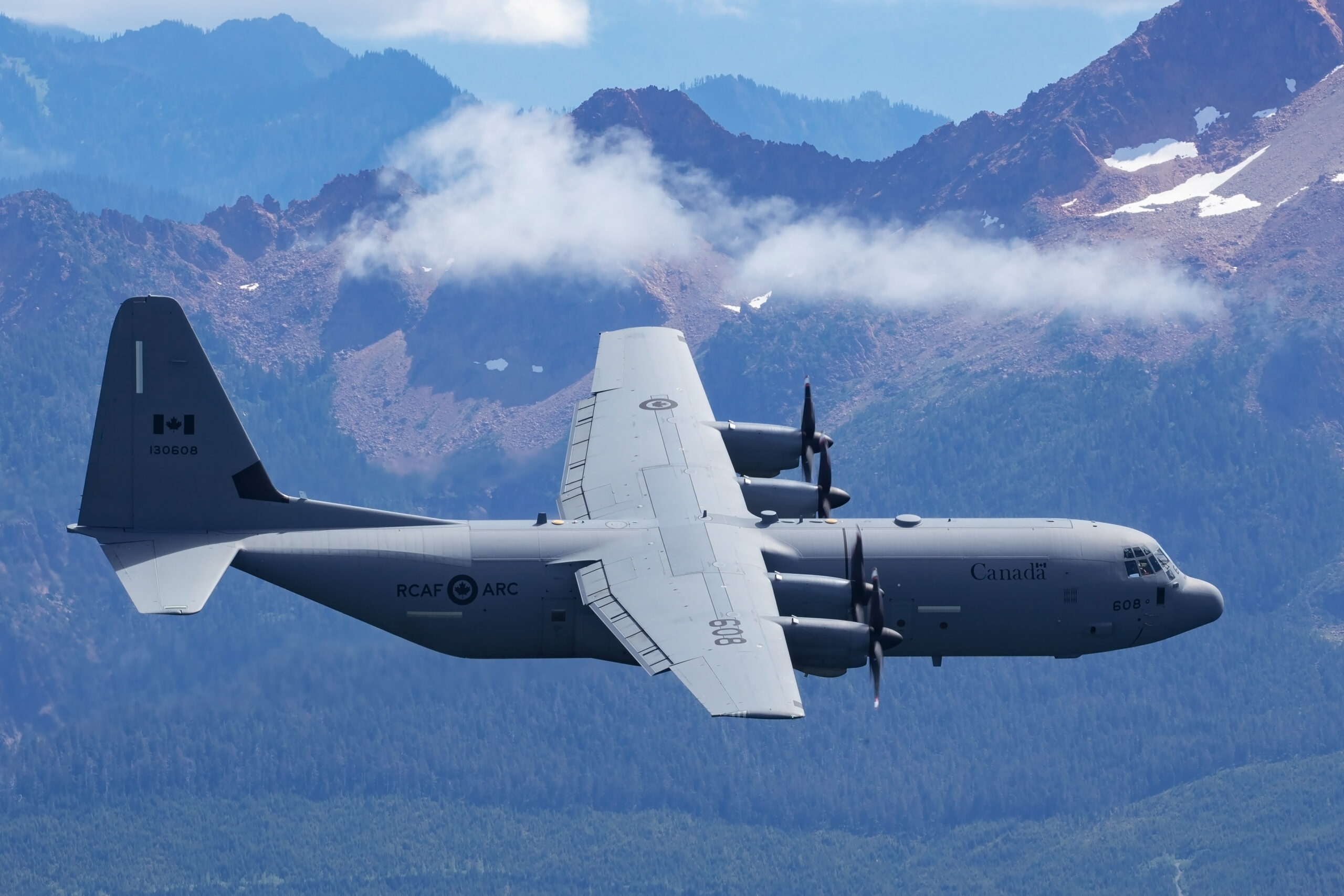 RCAF CC-130J Super Hercules 130608 side-on against rugged mountains, all four propellers blurred