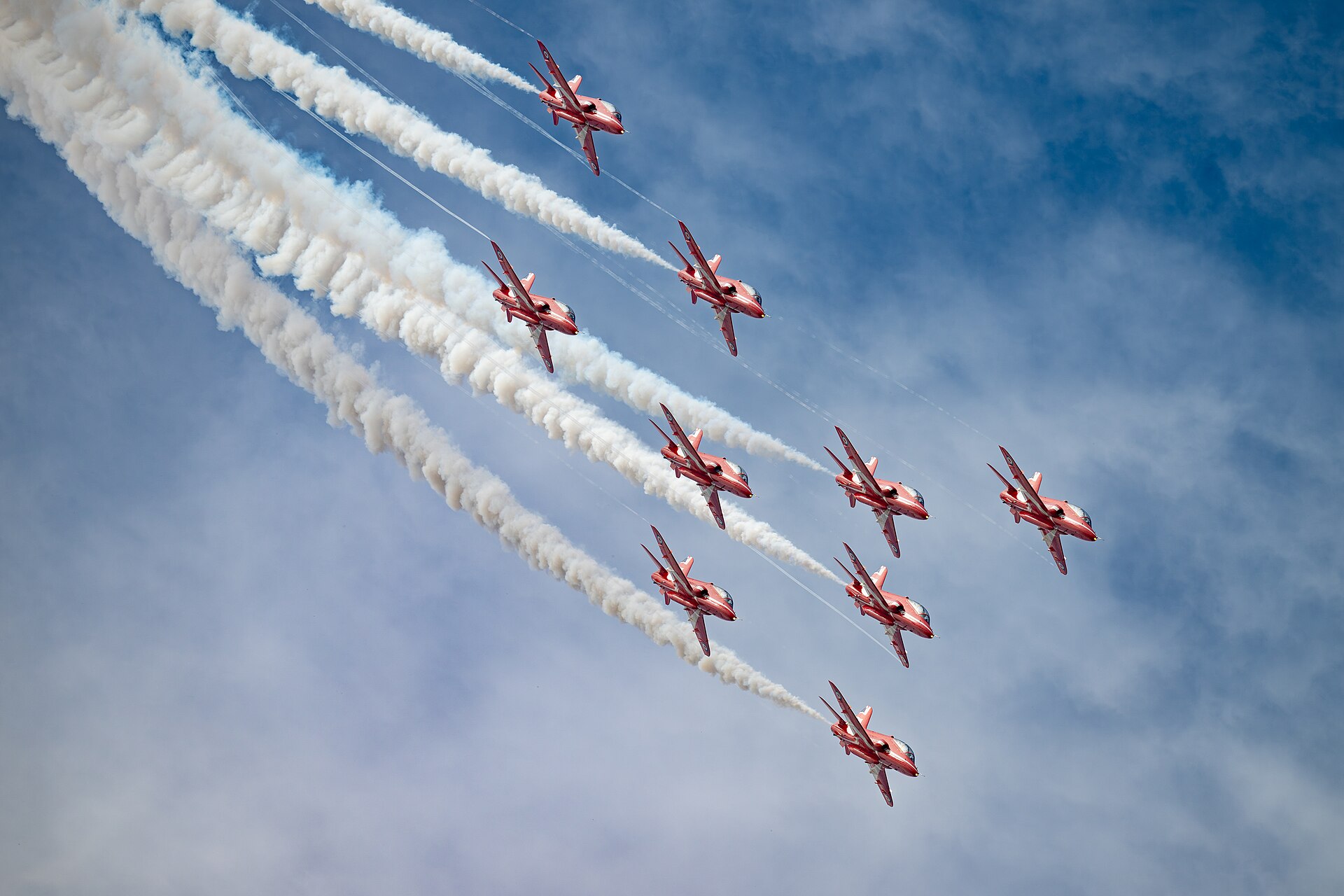 Red Arrows BAe Hawks looping in formation with red white and blue smoke at a UK airshow