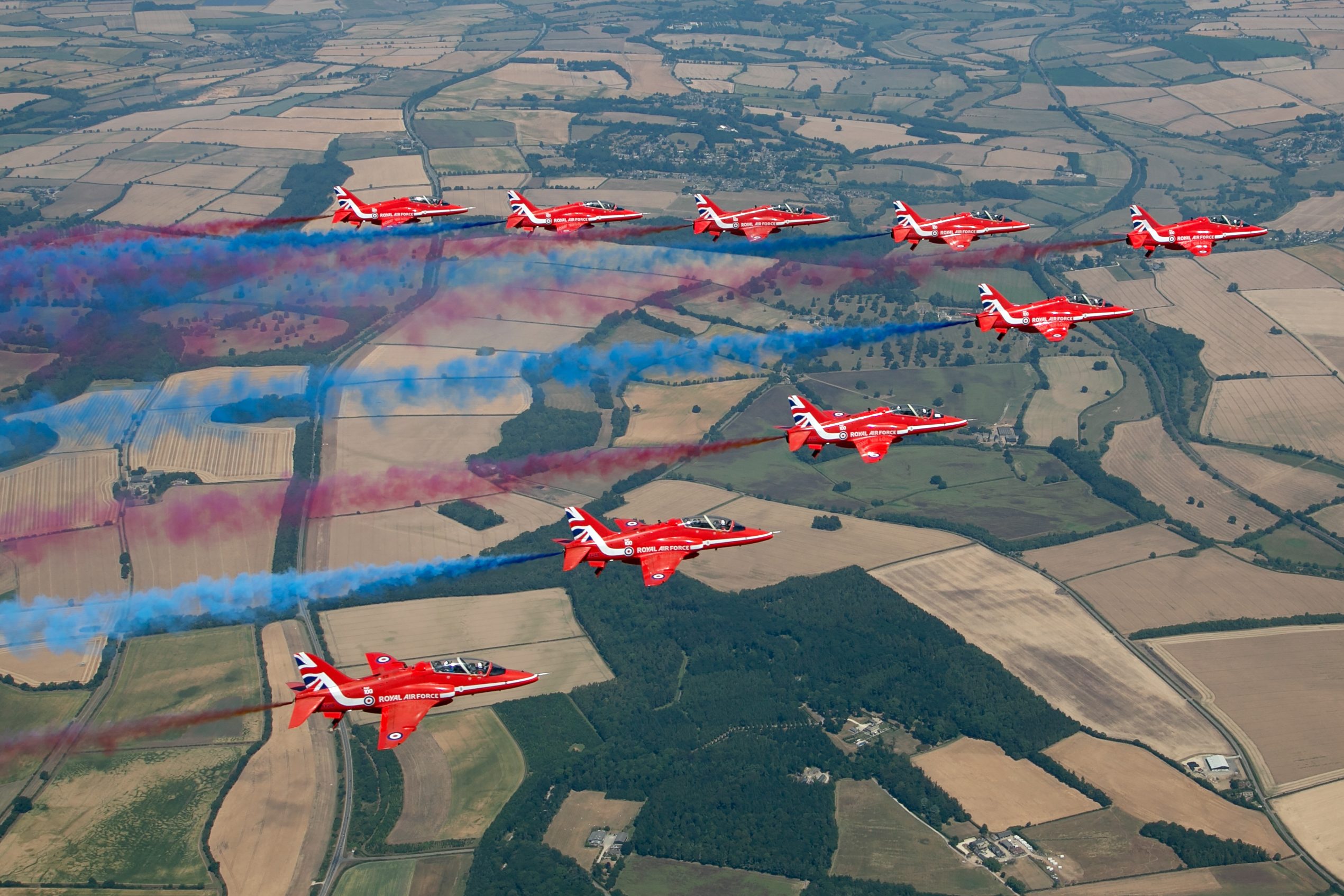 Red Arrows Hawk T1 formation banking tightly over the English countryside