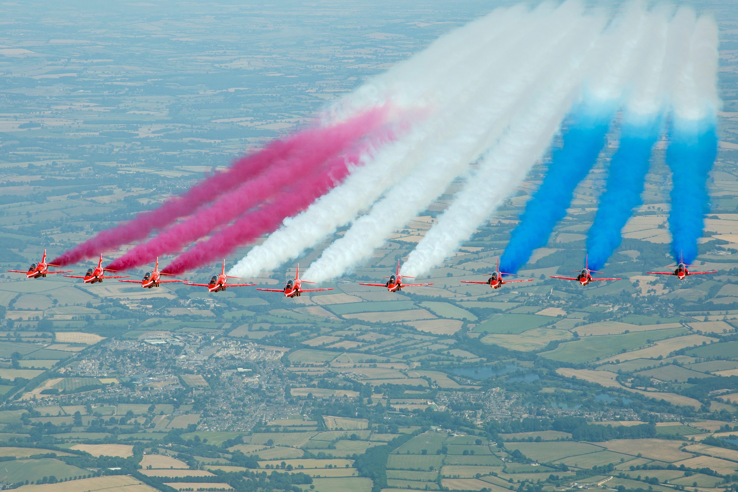 The Red Arrows in their BAE Hawk T1 jets trailing red, white and blue smoke seen from above