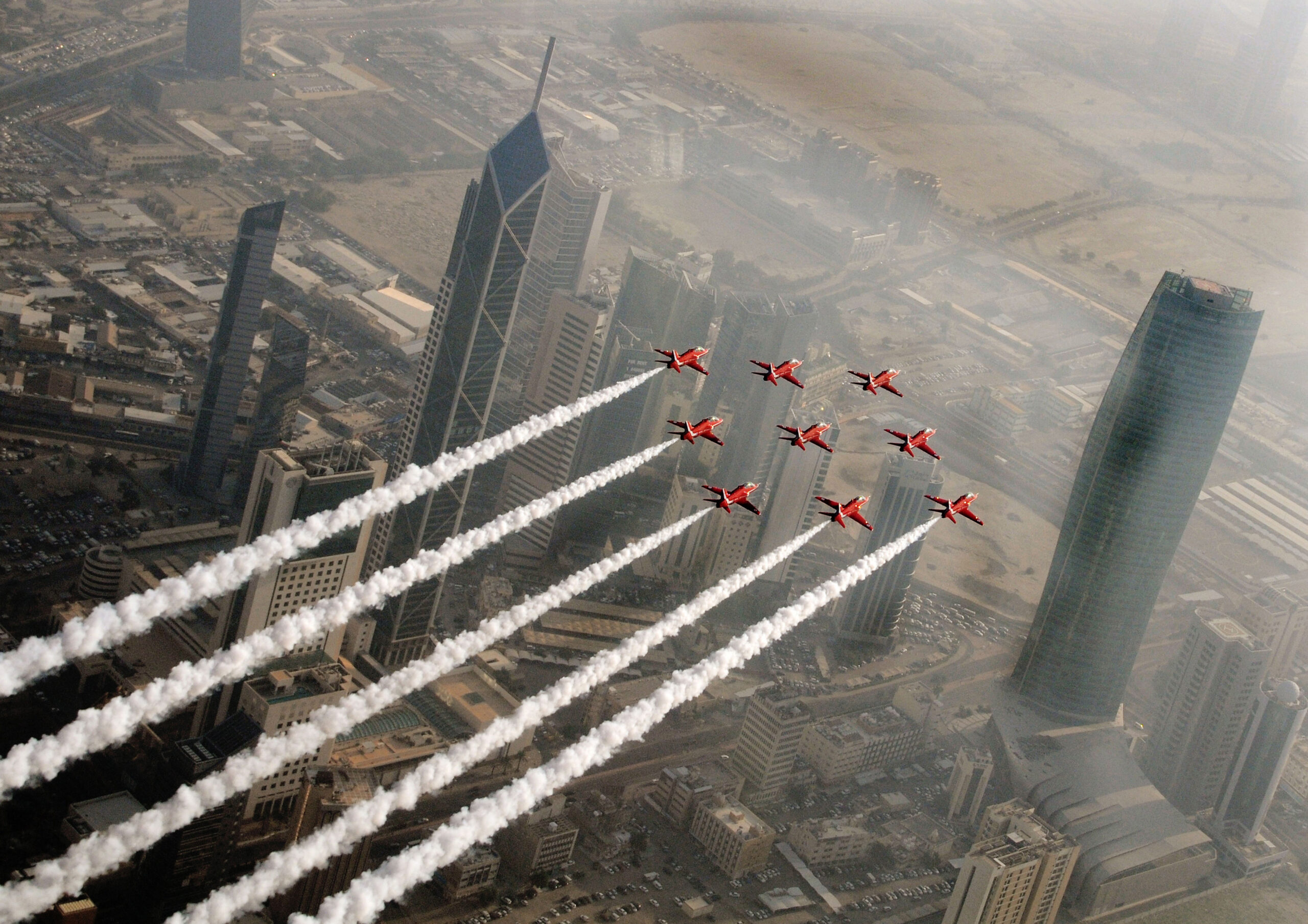 The Red Arrows flying in formation trailing smoke over Kuwait City