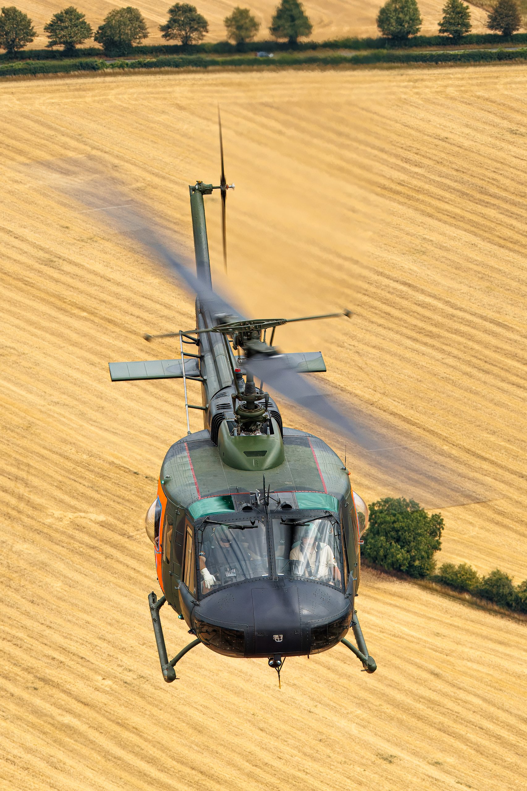 Bell UH-1D Iroquois helicopter low over golden fields
