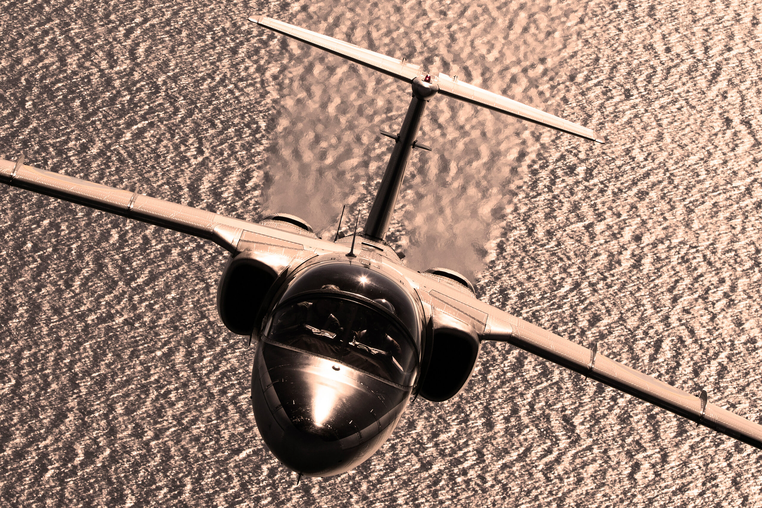 Swedish Air Force Saab SK 60B head-on against sunlit sea, backlit air to air