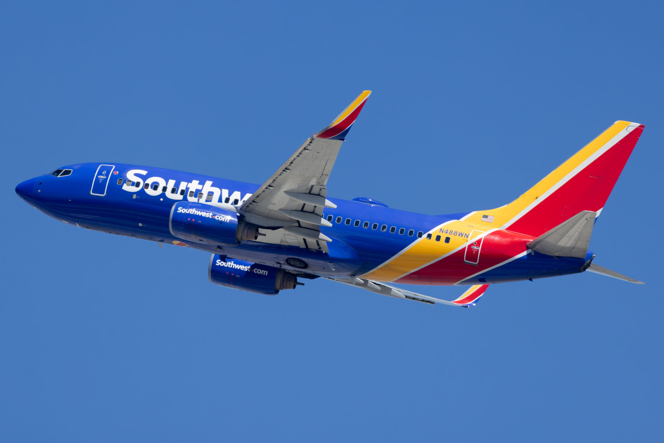 Southwest Airlines Boeing 737-700 N488WN in blue, red and yellow Heart livery climbing steeply after takeoff against clear blue sky