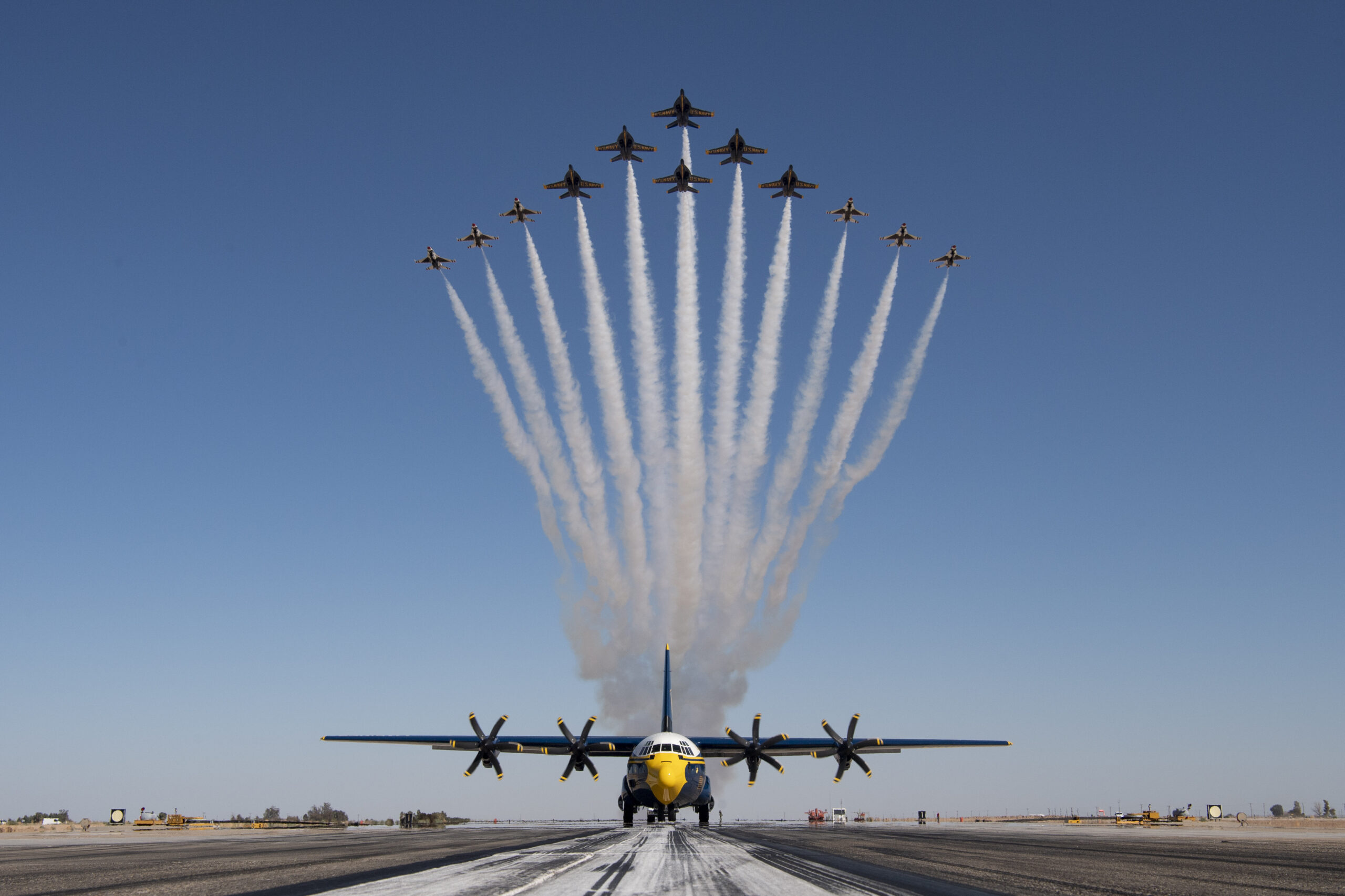 Thunderbirds F-16s and Blue Angels F/A-18 Super Hornets flying the Super Delta formation over a C-130J