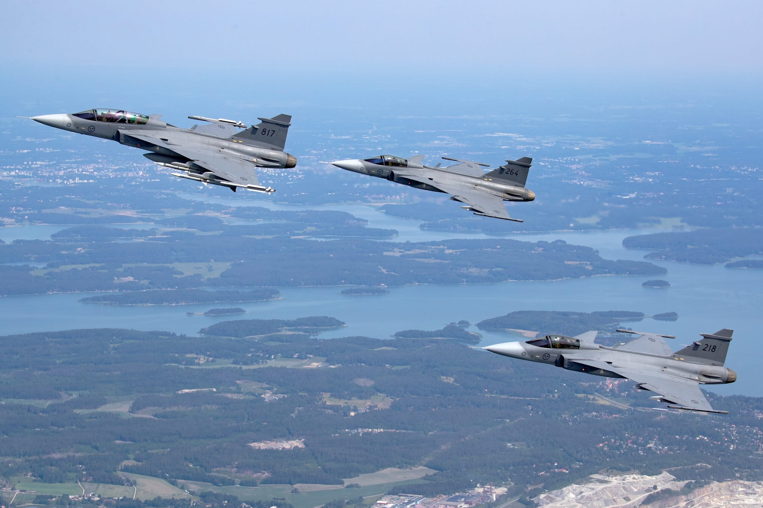 Three Swedish Air Force Gripens coded 817, 264 and 218 in formation over lakes and islands
