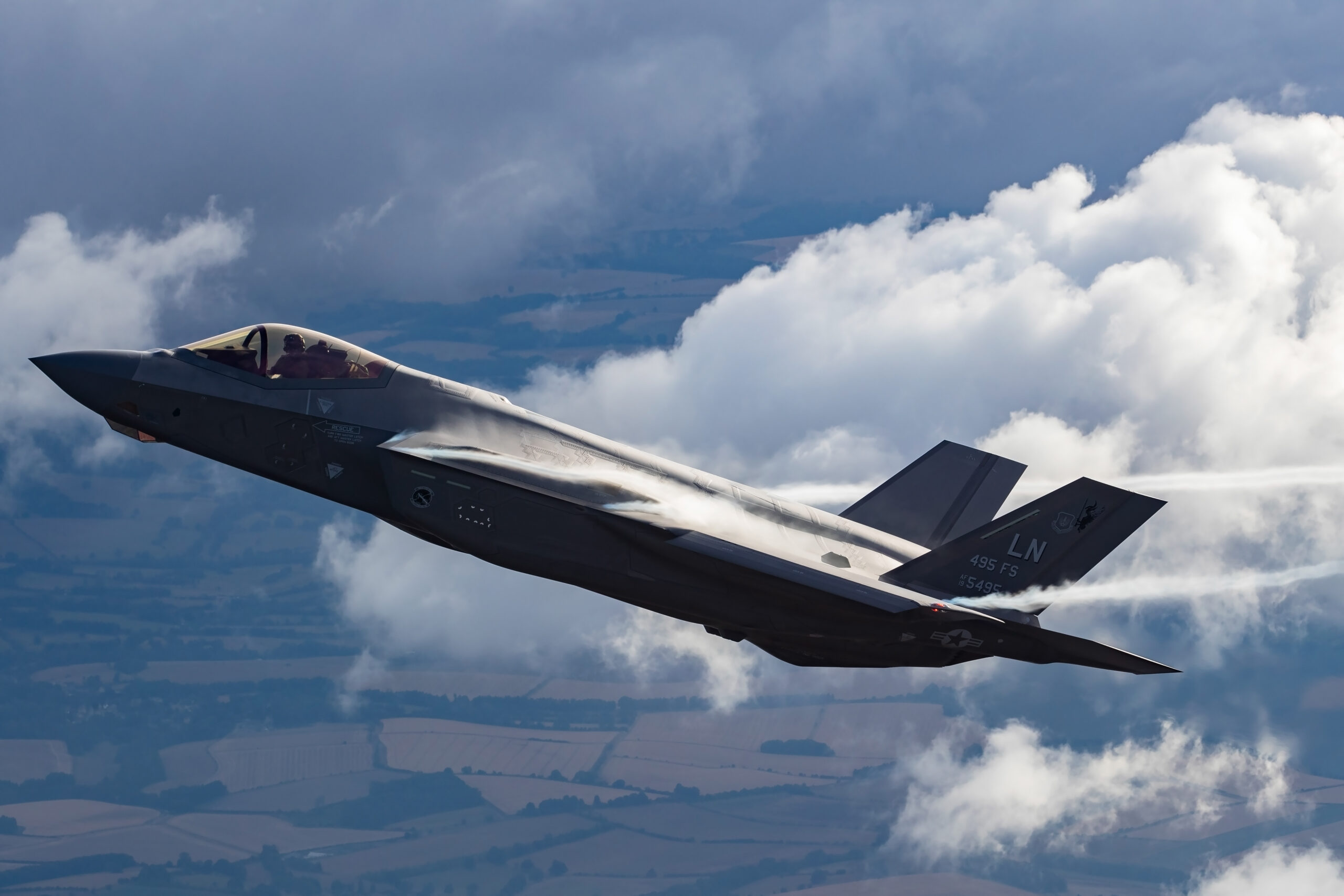 USAF F-35A Lightning II with LN tail codes pulling vapour past clouds
