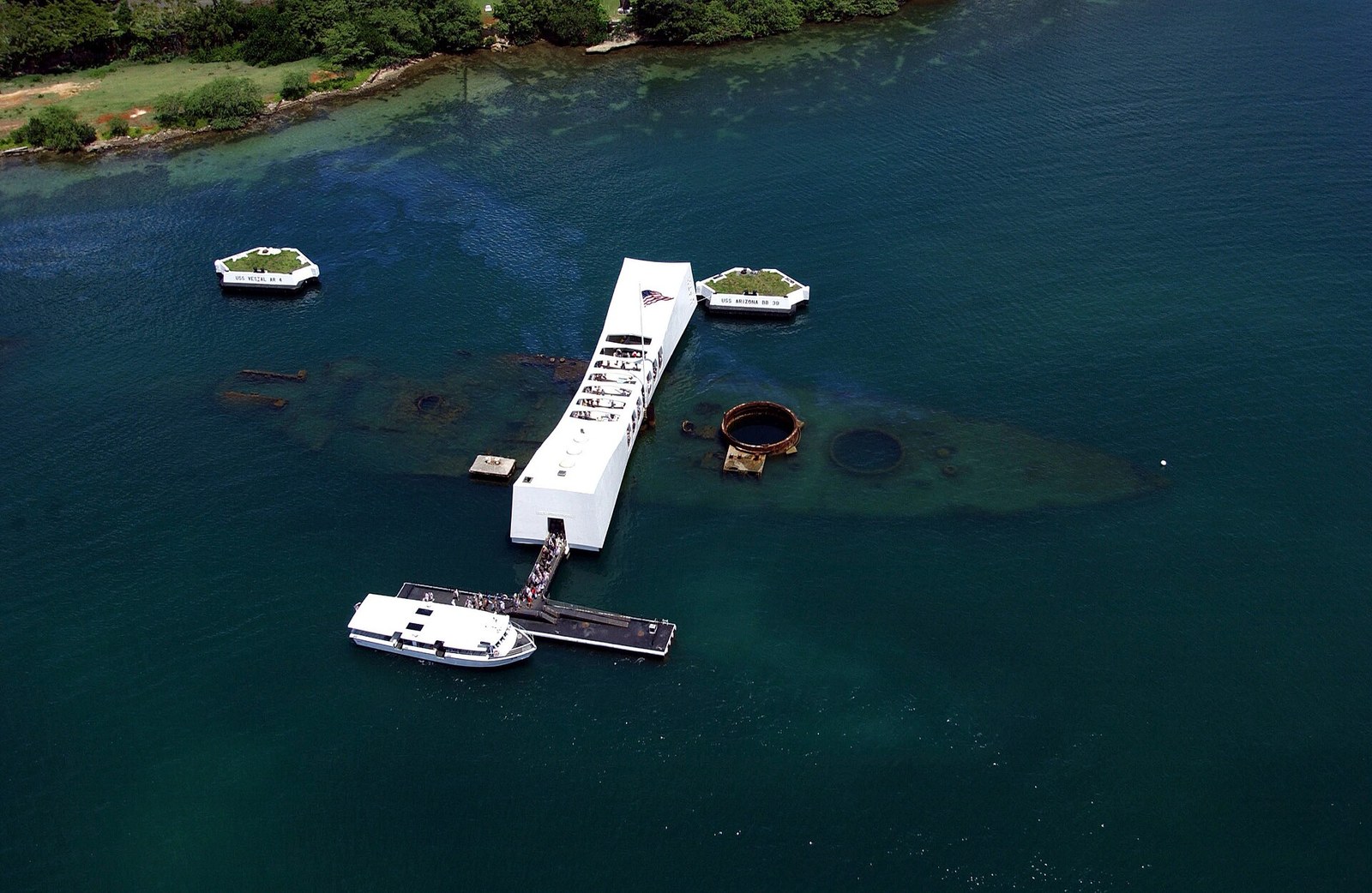 The USS Arizona Memorial seen from the air with the sunken hull visible through the water