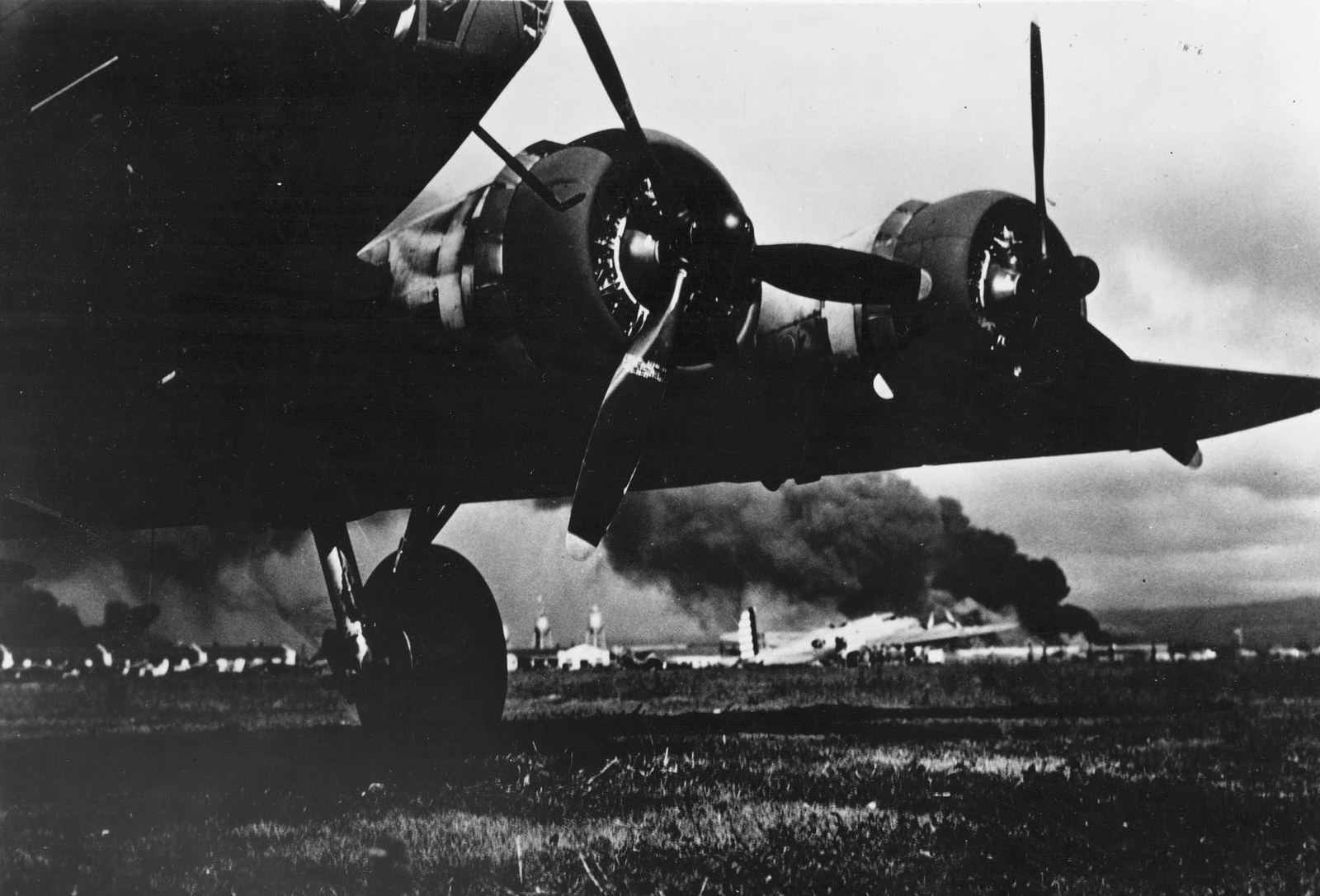Boeing B-17 silhouetted at Hickam Field with smoke rising behind it on 7 December 1941