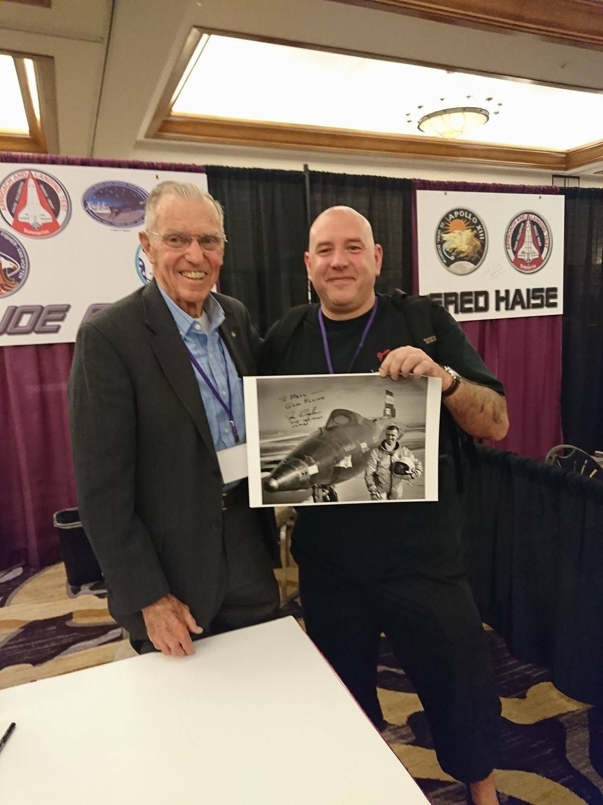 Joe Engle standing with Paul Fearn, who is holding a signed black and white photograph of Engle beside an X-15