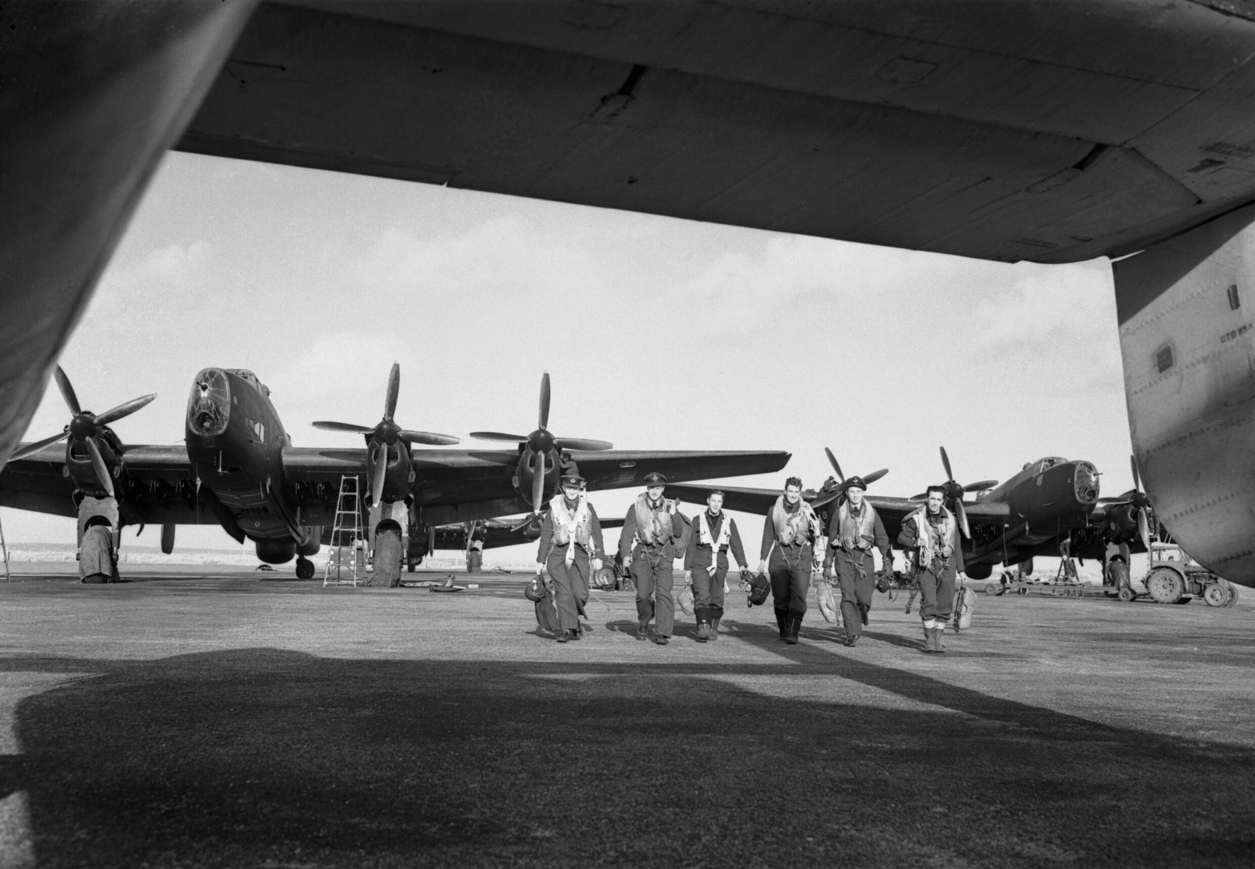 Aircrew walking beneath Handley Page Halifax Mk III bombers of No. 502 Squadron at Stornoway, February 1945