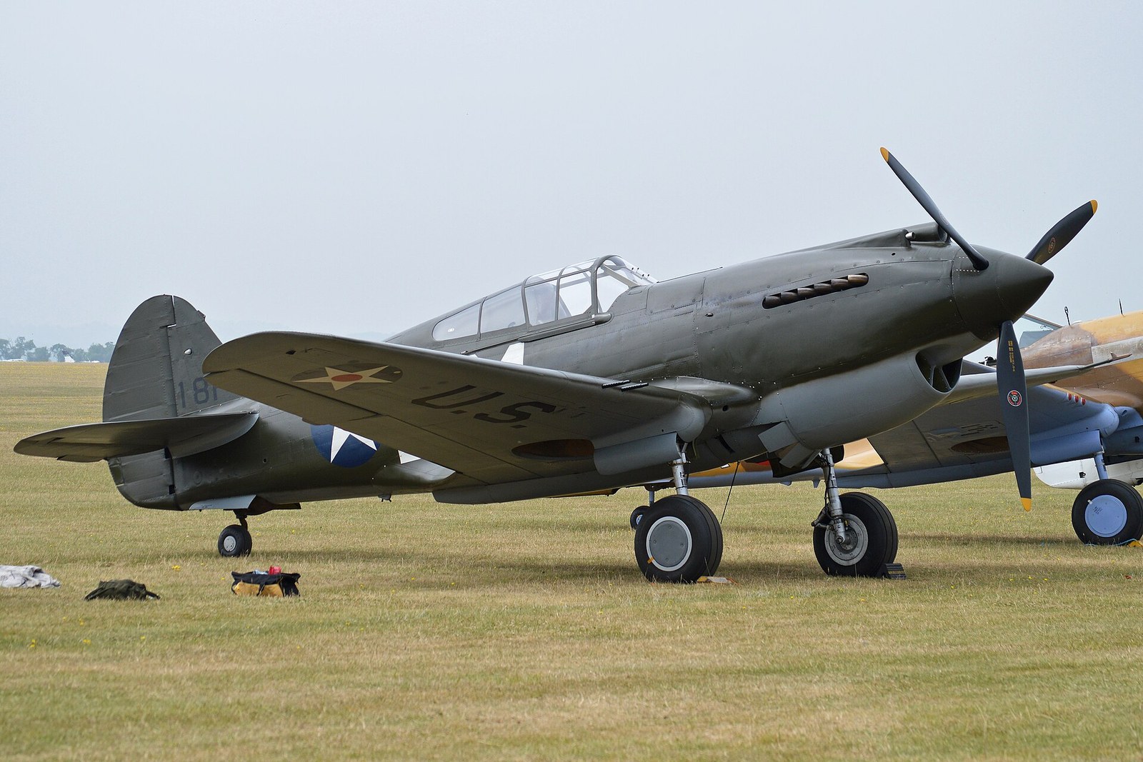 Curtiss P-40B fighter in olive drab standing on grass in pre-war United States markings