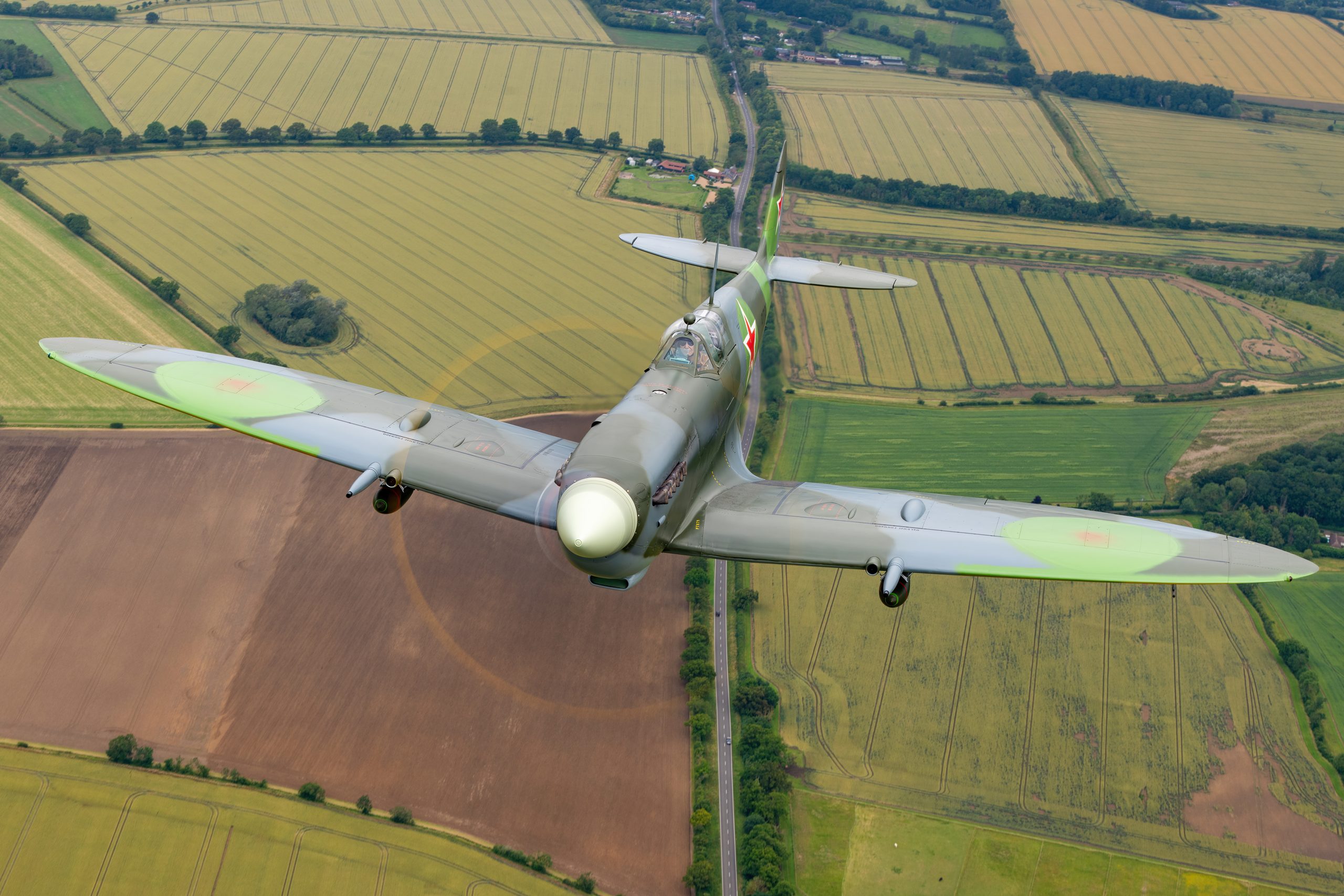 Topside view of a Supermarine Spitfire Mk IX banking over English farmland