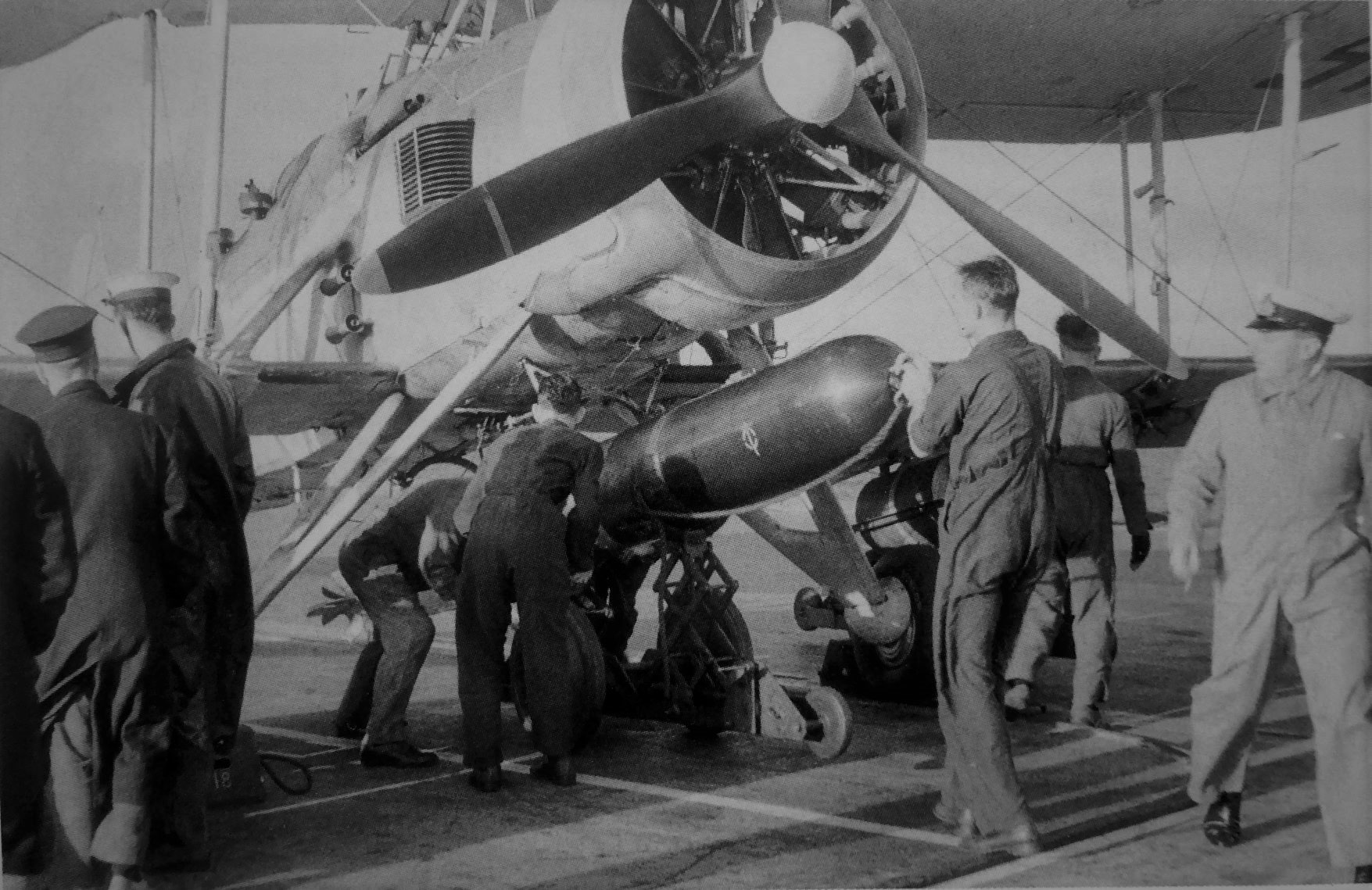 A Fairey Swordfish being loaded with a torpedo on the deck of HMS Ark Royal in 1941