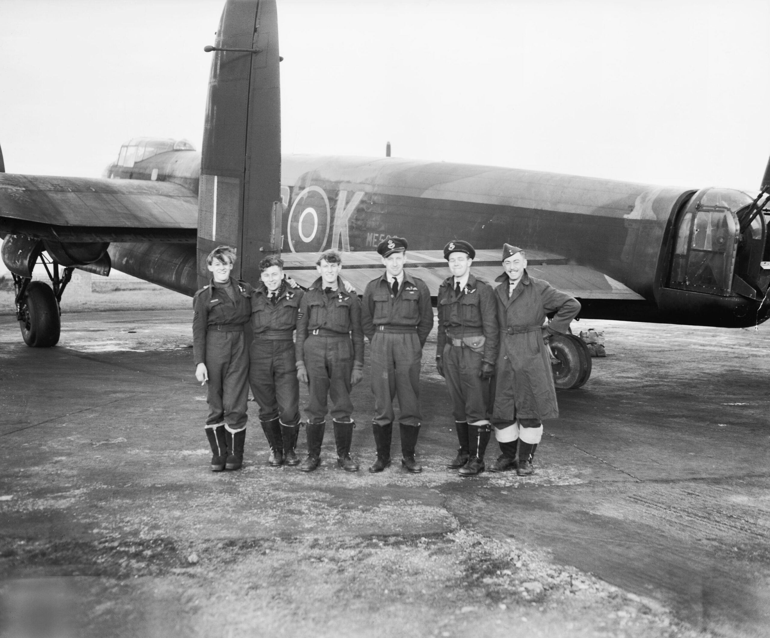 Aircrew of No. 617 Squadron standing beneath the rear fuselage of their Avro Lancaster