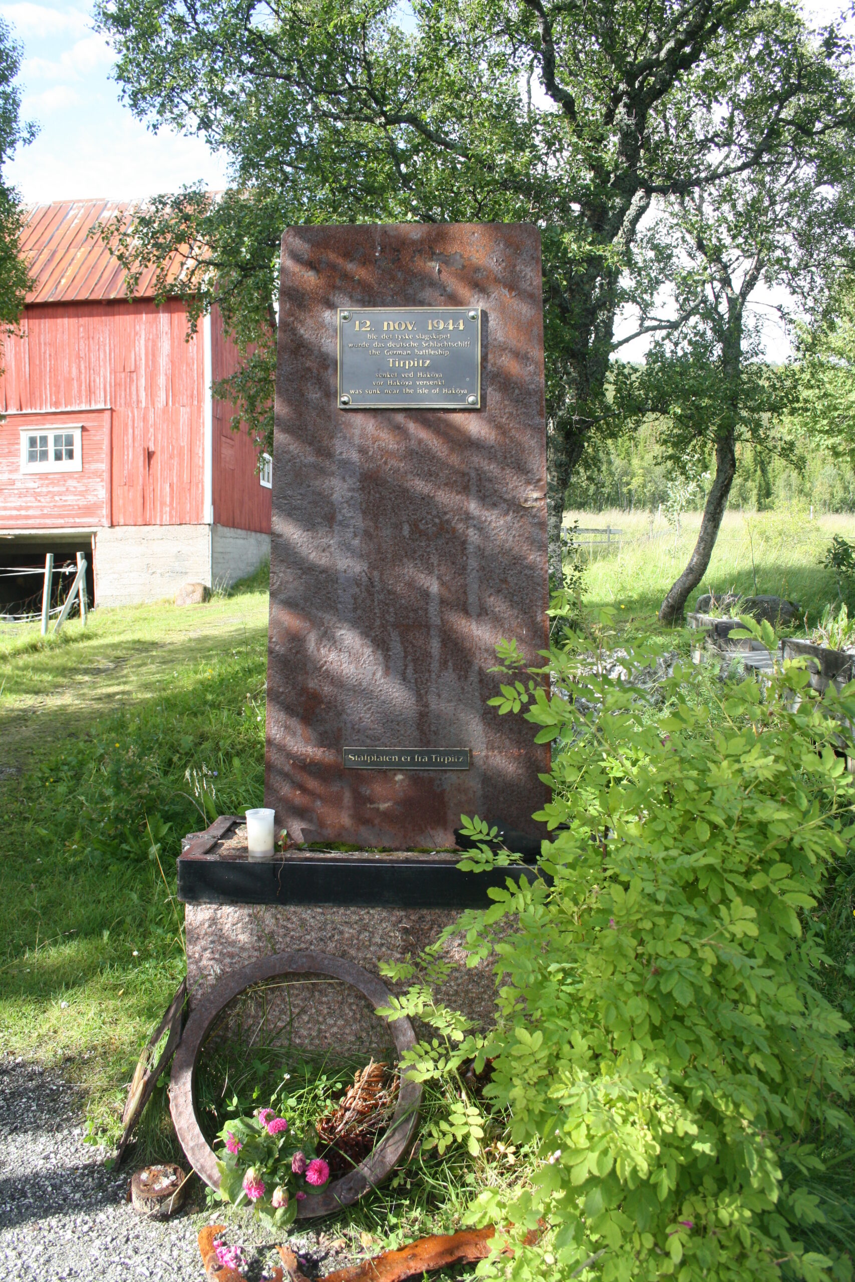 A memorial stone on the grass shore at Hakoya, looking out across the water towards the wreck site
