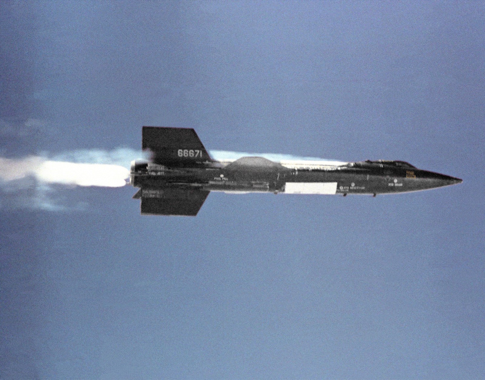An X-15 launching away from the B-52 carrier aircraft with its rocket engine burning